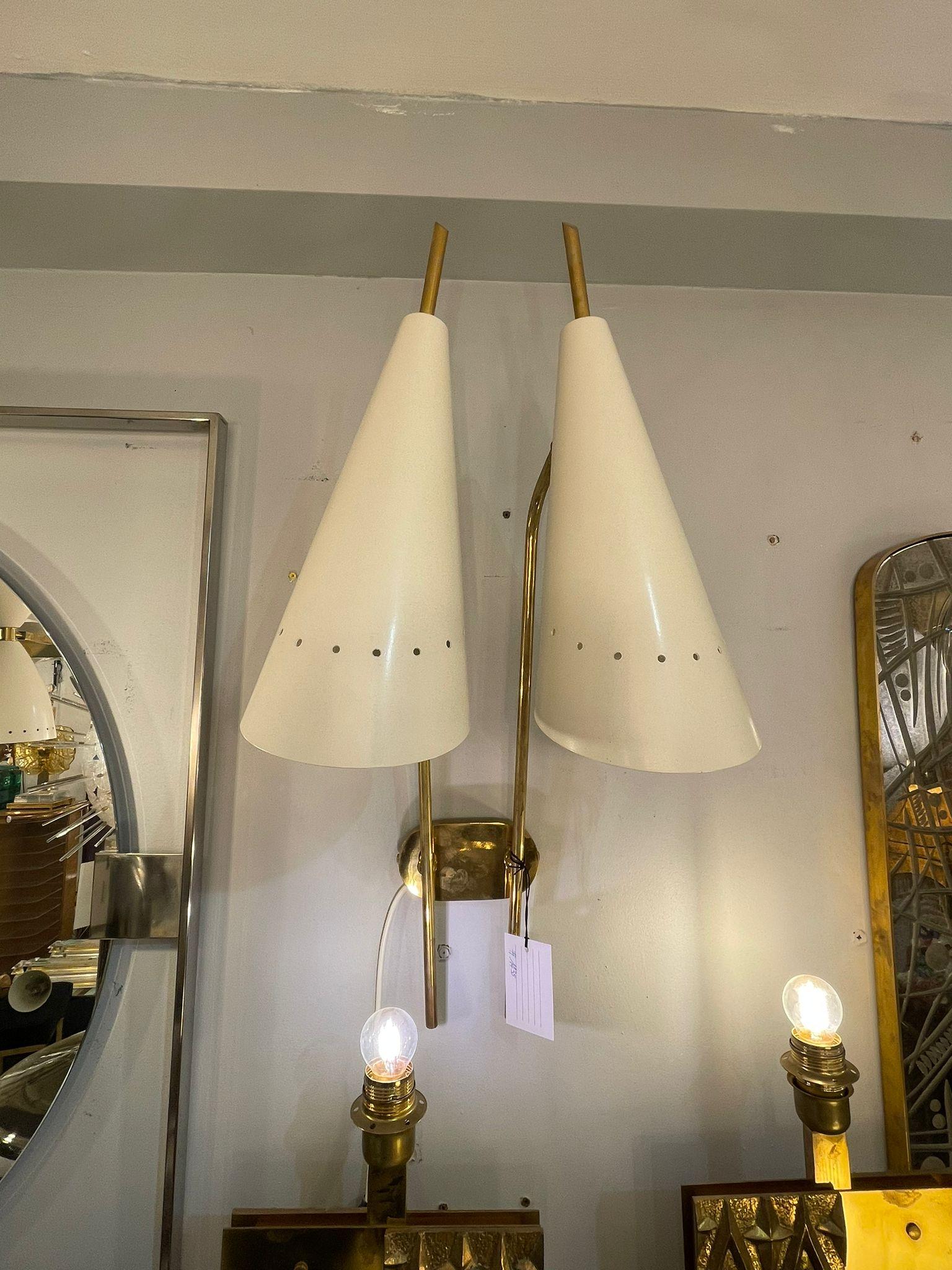 A pair of elegant Italian Wall lights in brass and shades in ivory, in the style of Stilnovo. Circa 1970s.