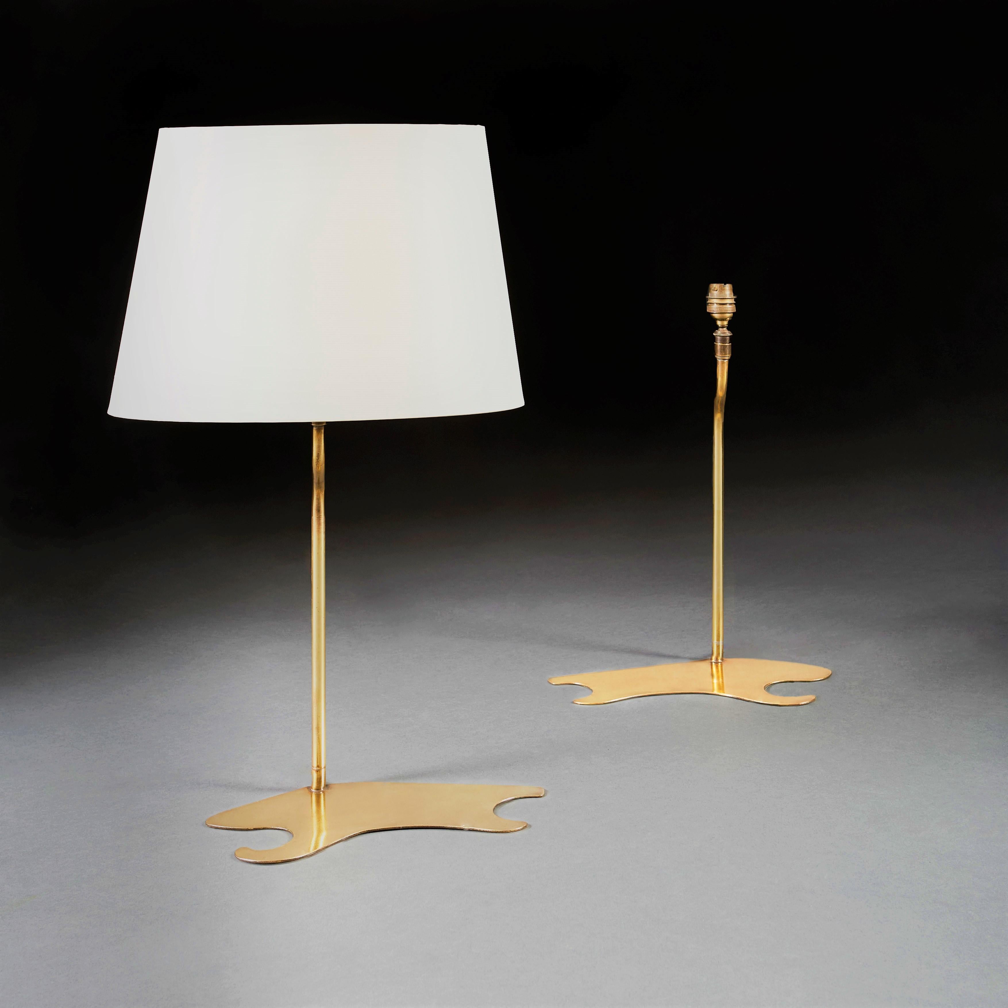 A pair of mid-20th century brass lamps, the bases in the form of a painter’s palette, the stems with an elegant bed to the neck, with a pair of bespoke oval silk shades.

Currently wired for the UK.