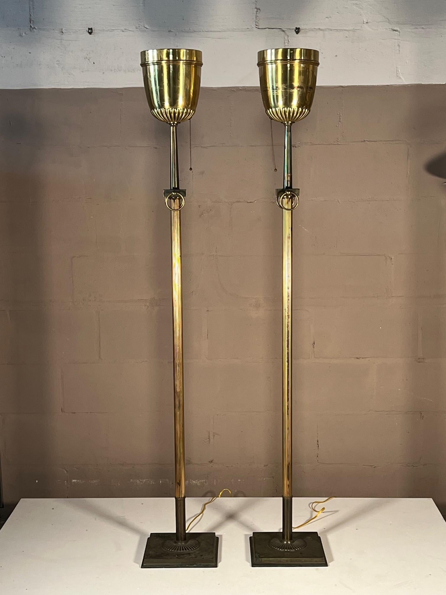 A pair of stylish vintage brass torchères in Paavo Tynell/Lightolier style. Elegant with nice patina and tarnishing, pull down chain switches. Each one has a pair of decorative rings on top.