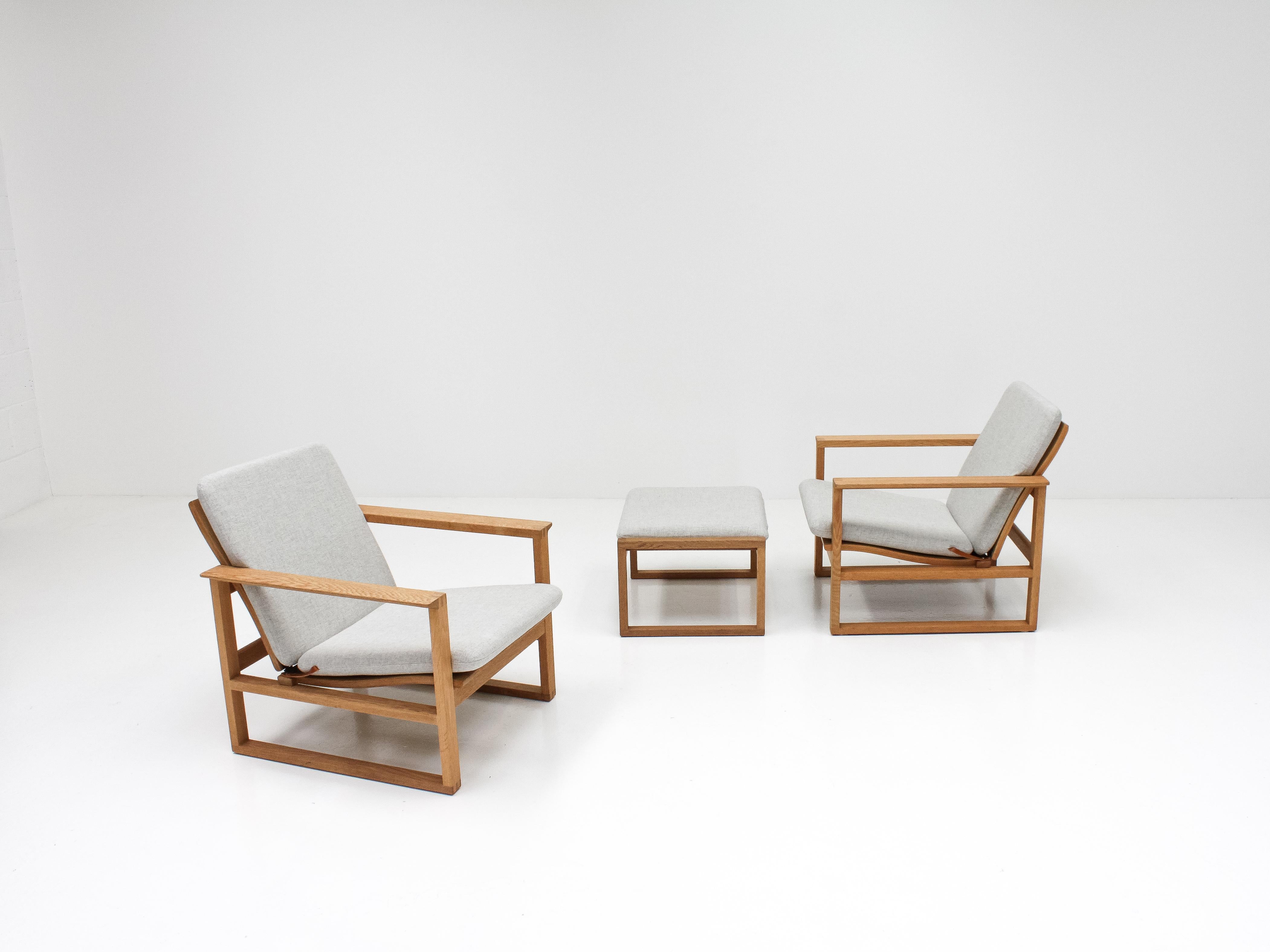 A pair of Børge Mogensen lounge chairs with footstool designed in 1956, model number 2256 for Fredericia Stolefabrik. 

The chairs consist of cubical frames made of solid oak with finger joints. Newly reupholstered in Kvadrat Tonica, a beautiful