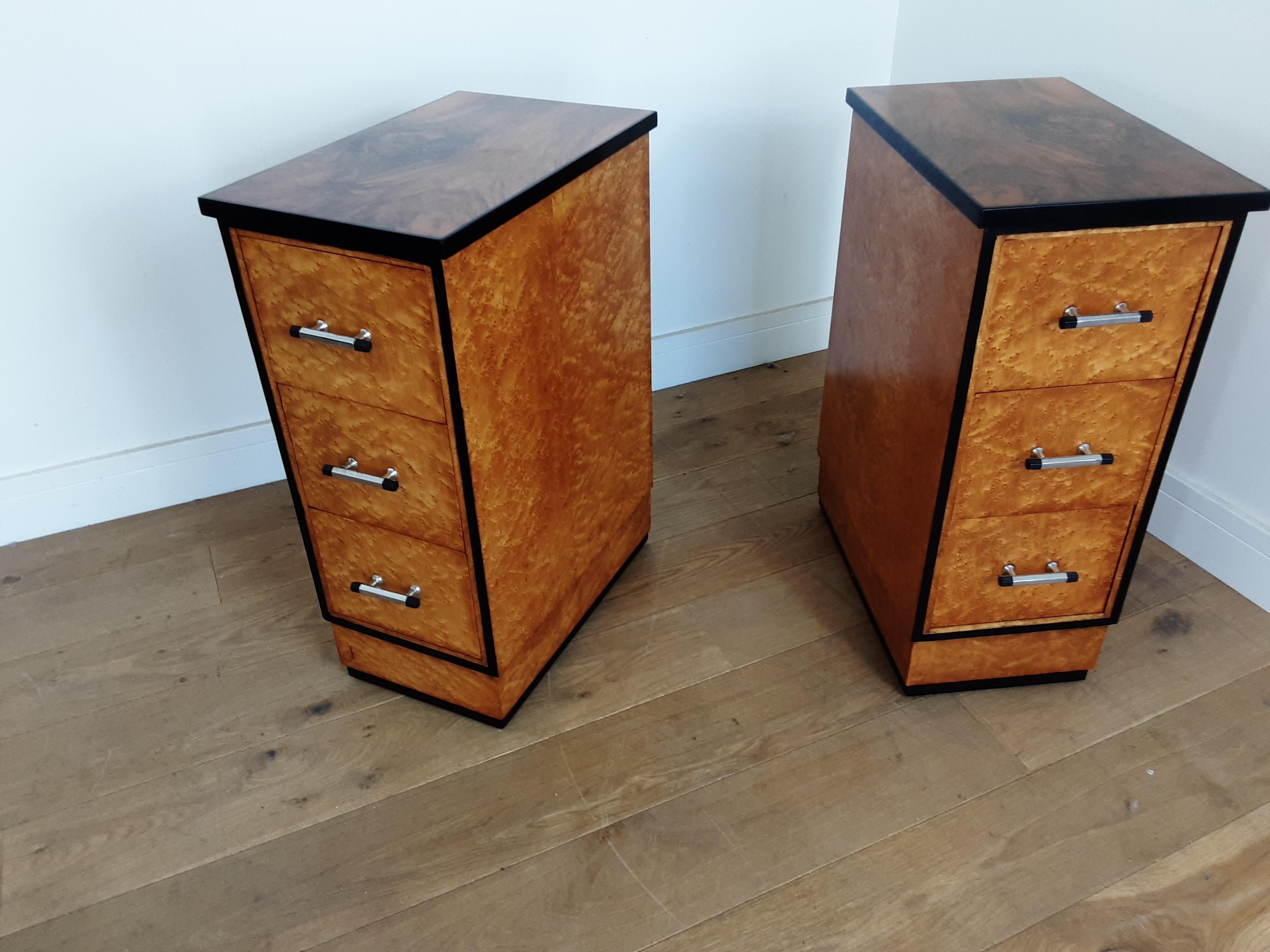 A pair of three drawer bedside cabinets.
These are very smart with bird's-eye maple and an ebonized wood trim, and chrome and black handles, the top finished in a stunning figured walnut.
designed by Harry and Lou Epstein
Measures: 71 cm H 31 cm