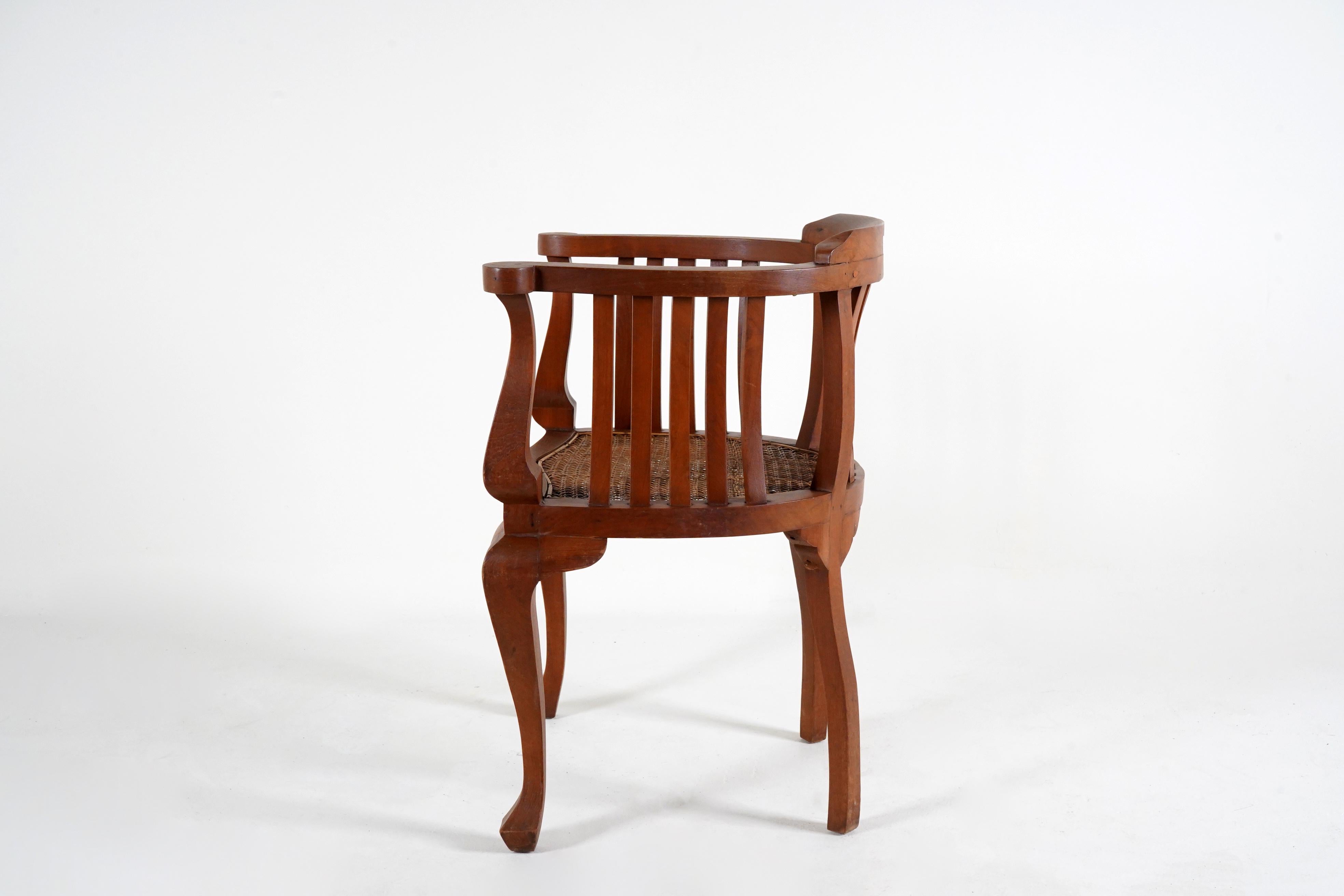 These stylish British Raj armchairs are hand carved from teak and fitted with woven rattan seats. The cabriole legs and arms are graceful and beautiful from every angle. The barrel style back is very comfortable and the woven seat provides