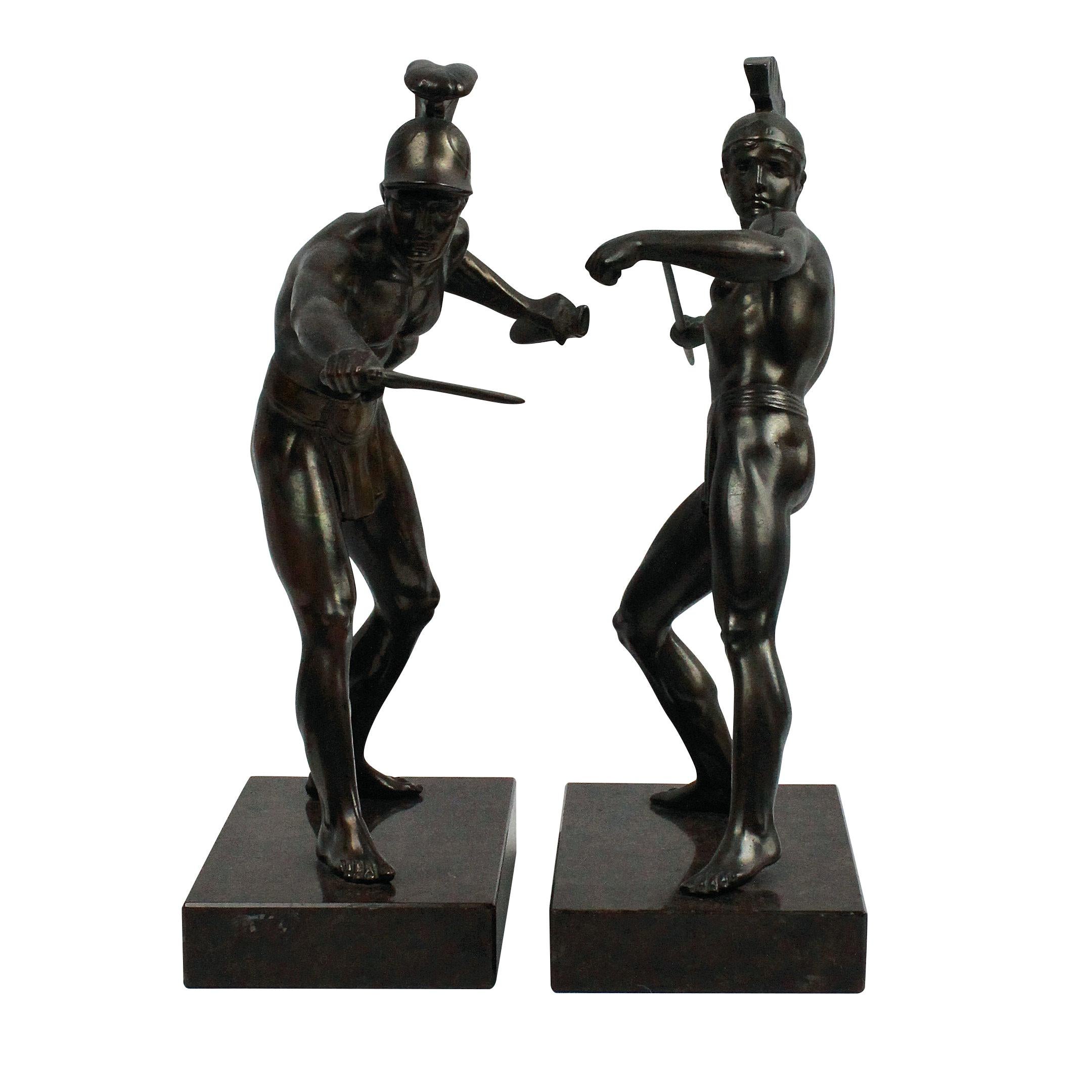 A pair of English bronzes of ancient Greek warriors on dark brown polished marble bases, one holding a spear and the other a sword.