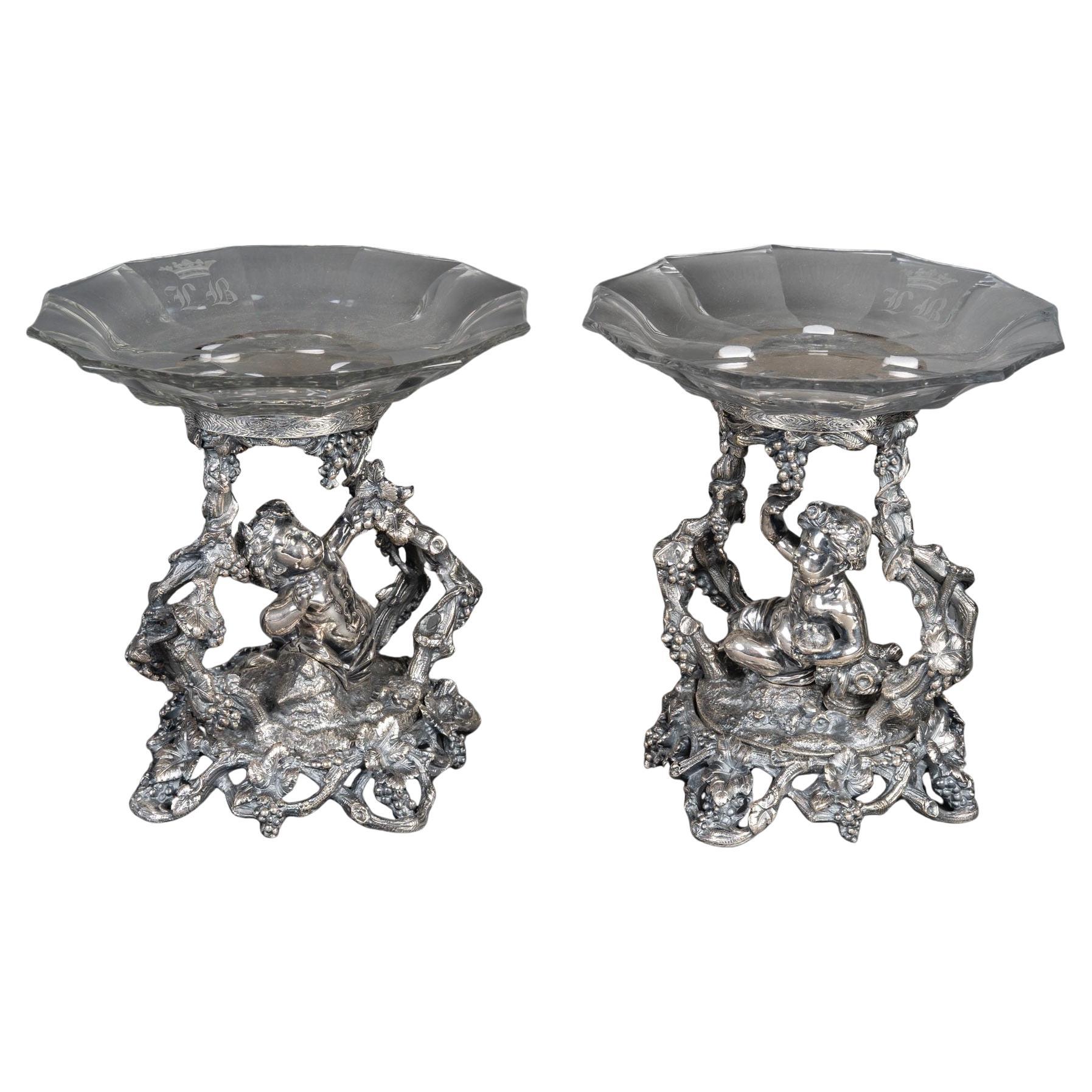 A Silvered Bronze and Baccarat Crystal Pair of Compotiers
Representing two silvered bronze cherubs, one with birds, the other one picking grapes, the mounts simulating branches, foliages, leaves and grapevines.
Each one is supporting a Baccarat