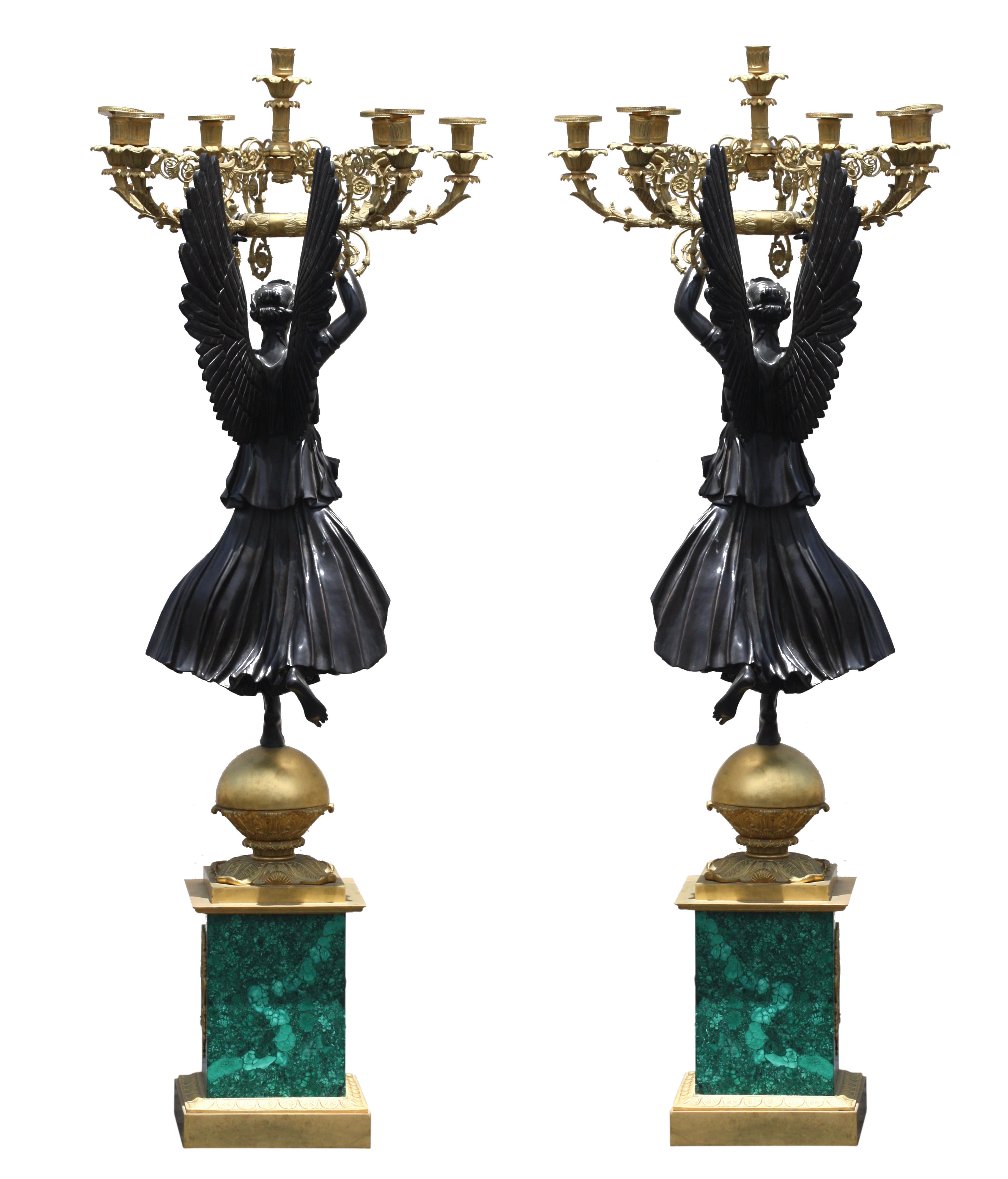 A Pair of Bronze and Malachite candelabra
Empire Style, 20th Century, with seven foliate lights, held by a Renommée on a sphere, on a quadrangular malachite base, Height 52 in. (132.08 cm.), 19 inches across (48.26 cm.).
 