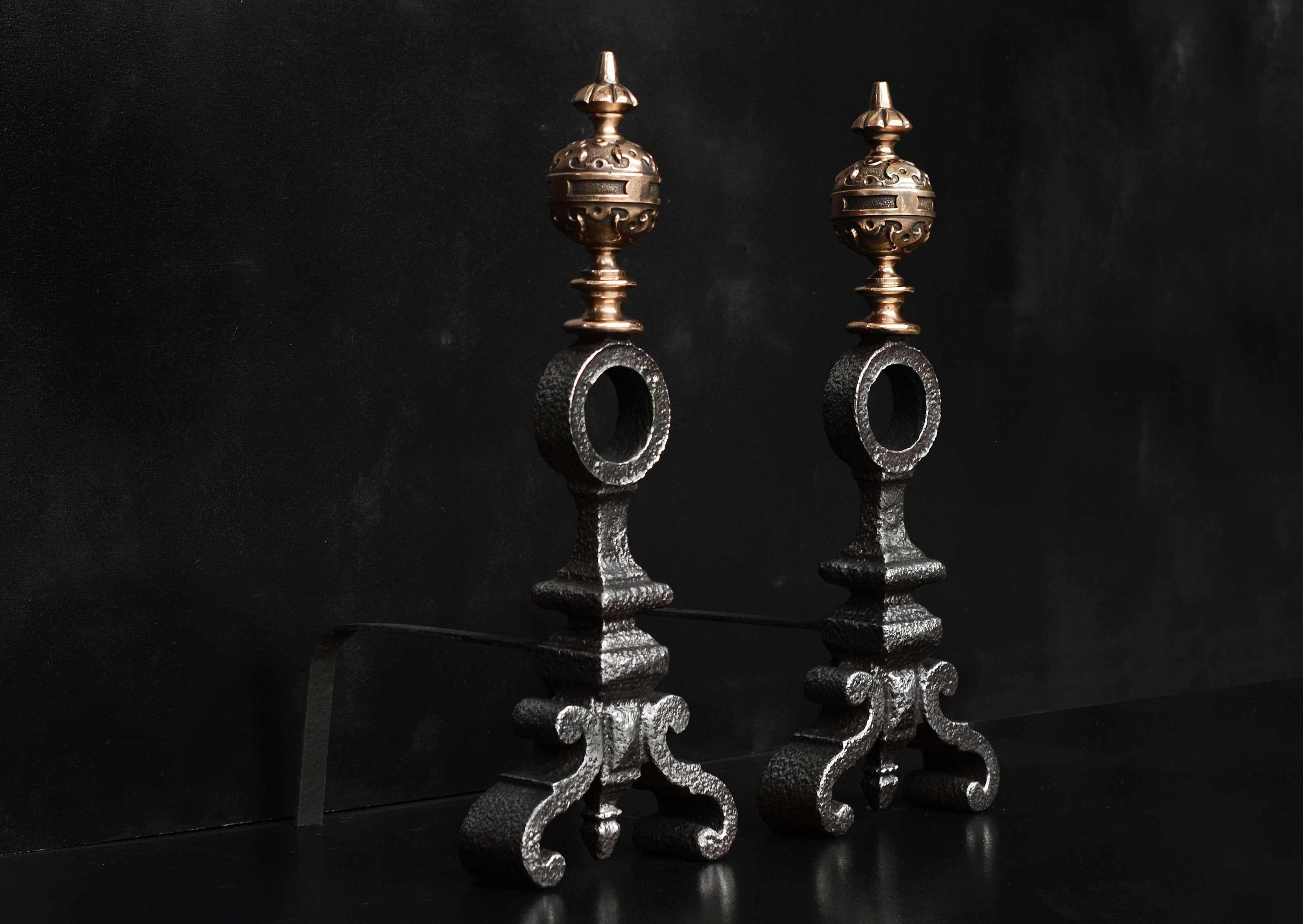 A pair of Baroque style firedogs. The cast iron body with circular detail to centre, surmounted by bronze finials with sphere of spherical form. English, second half of 19th century.

Measures: Height: 560 mm 22