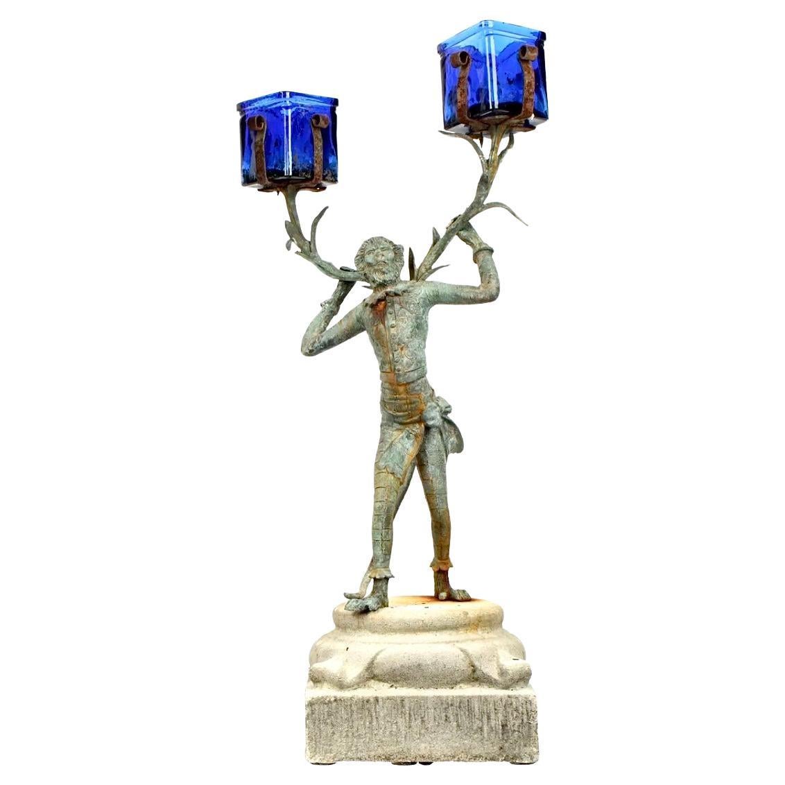 Coppia unica di portacandele in bronzo raffigurante una scimmia maggiordomo. Le braccia tese delle scimmie sostengono due portacandele in vetro blu cobalto. Le scimmie riposano su basi di cemento. Questi portacandele uniscono l'estro all'eleganza e