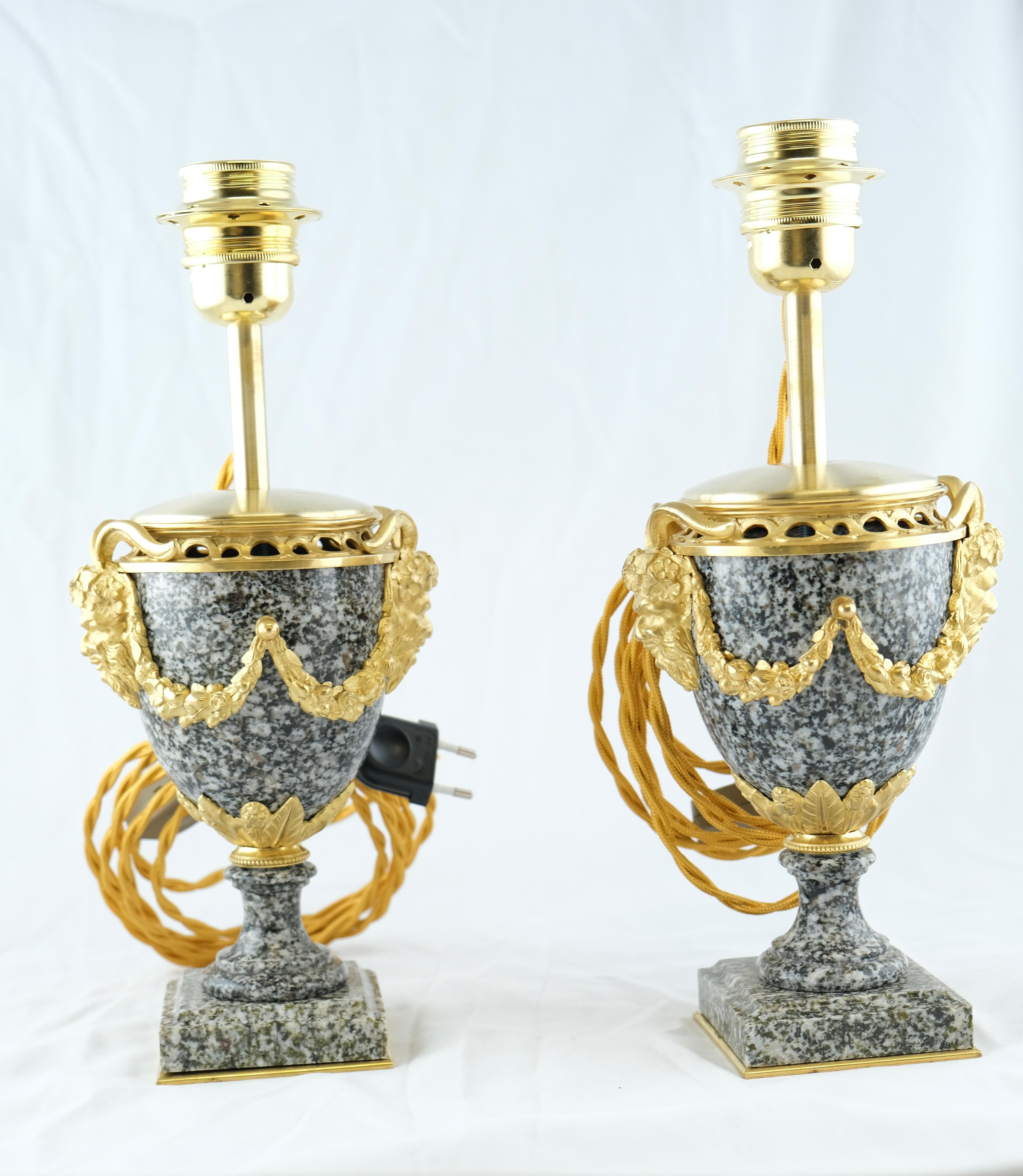 An attractive pair of granite urns mounted with gilt bronze decorations. The urns are electrified and mounted as lamps. The bronzes are of good quality as well as the granite urns.
 
