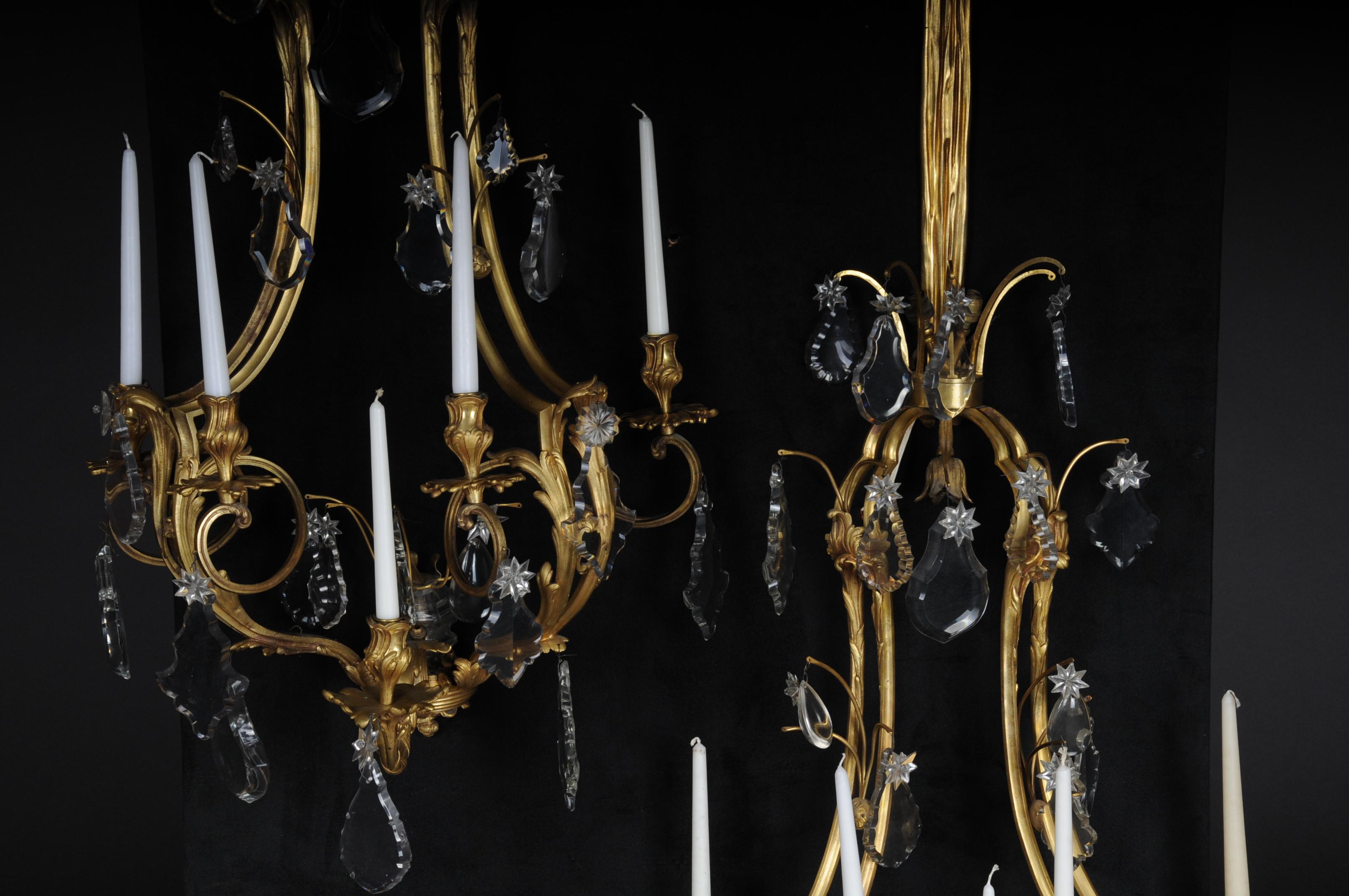 A pair of bronze splendor wall appliqués / sconces, Paris, 19th century

Fire gilded bronze. Five-flame frame for candles with rocaille and rosettes in relief. Colorless glass prism curtain. Three-flame top with electrification, France, 19th