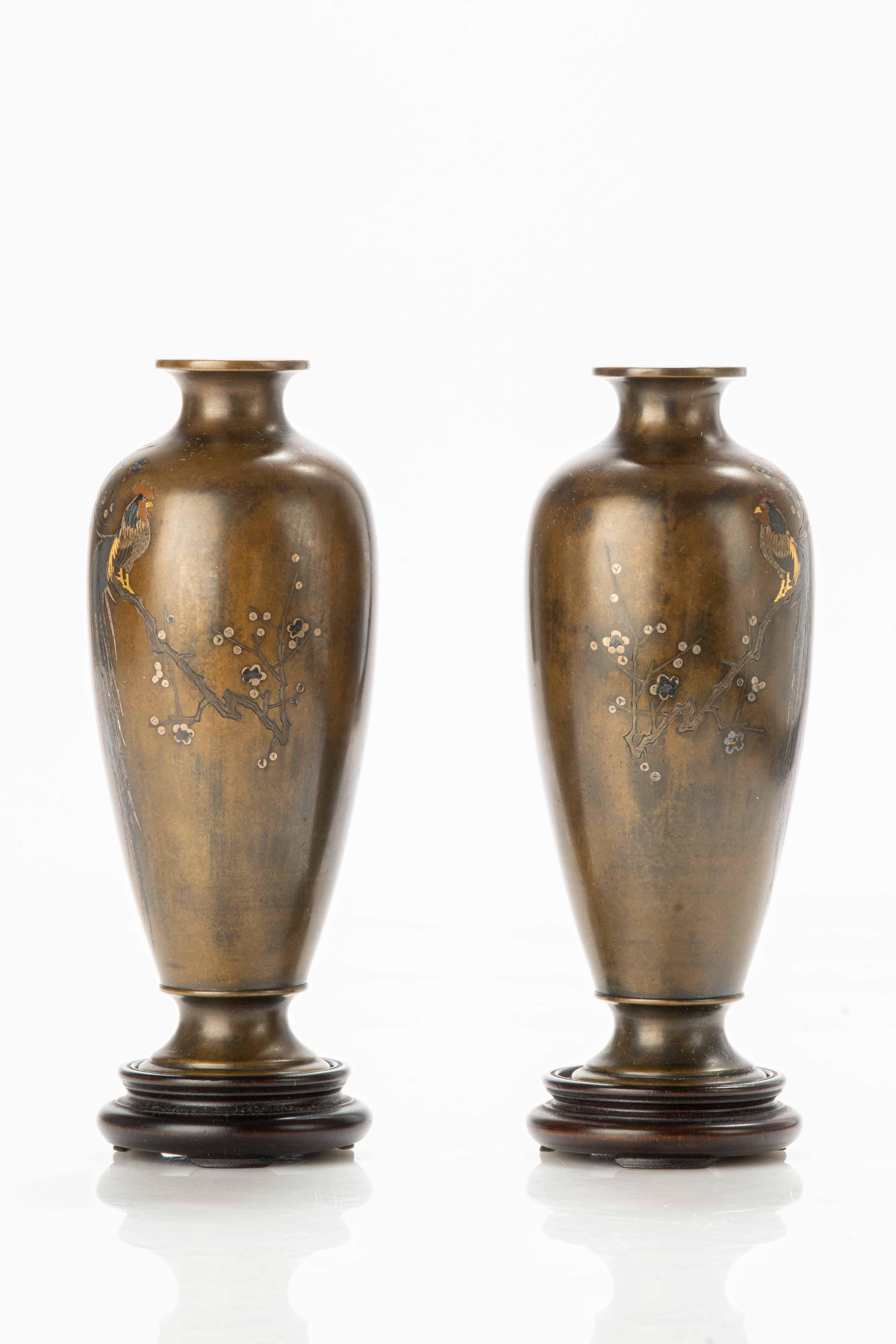 Pair of bronze vases adorned with inlays, decorated with two Onagadori roosters, known for their elegant length of tail. The roosters are represented perched on a plum branch.

Signed by Yoshimasa for Nogawa company.

Period: Meiji end of 19th