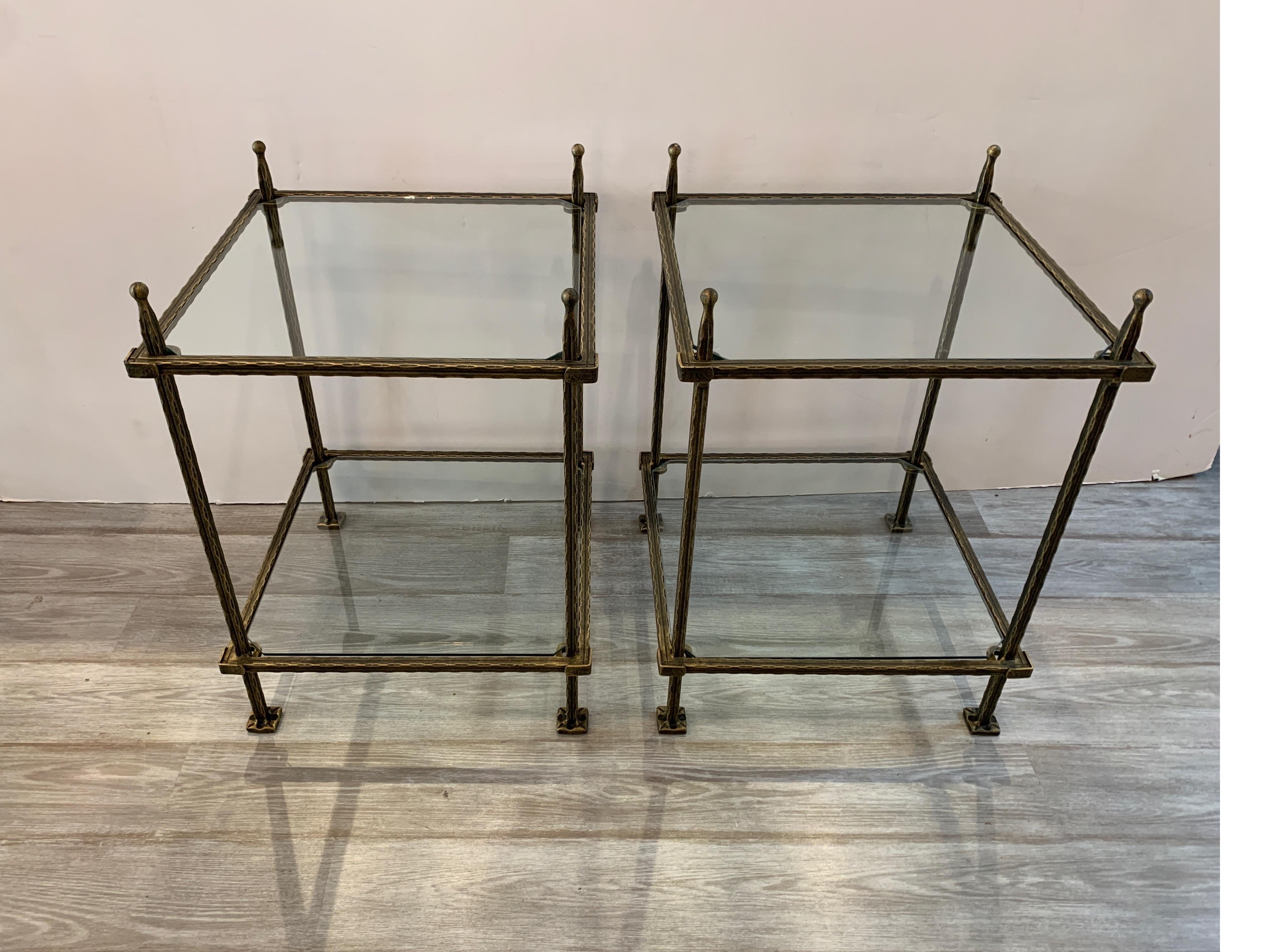 A pair of bronzed finish two tiered tables with glass tops. The frames with a gilt and black washed finish. By Italian maker Claudio Rayes, 1970s The height to the top glass tier is 25 inches, the top of the table with finial is 28 inches.