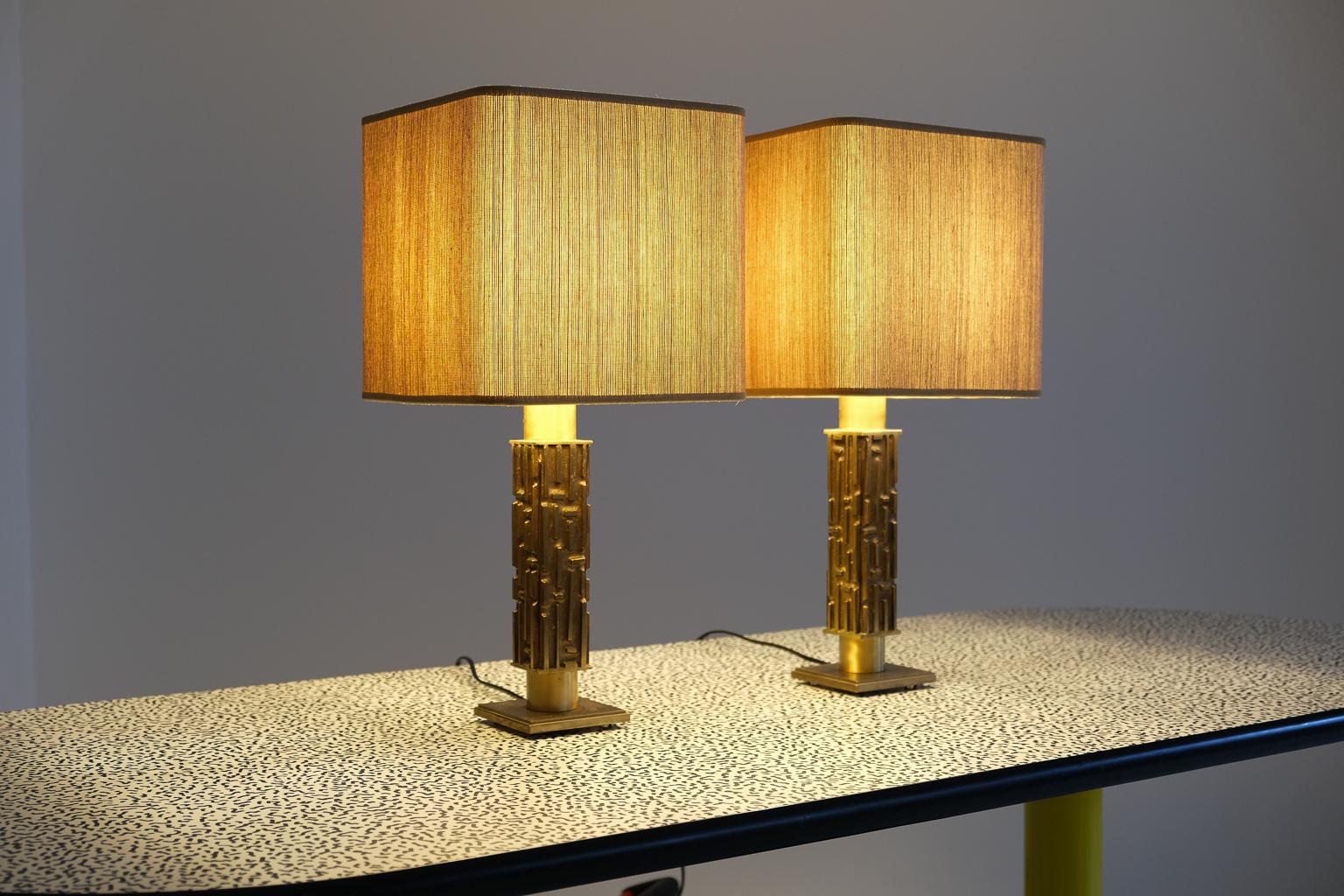a pair of table lamps by angelo brotto. the lamp base is made of solid brass with a sculptural structure. the square lampshades are newly made and covered with seagrass paper. the electrics have been renewed.