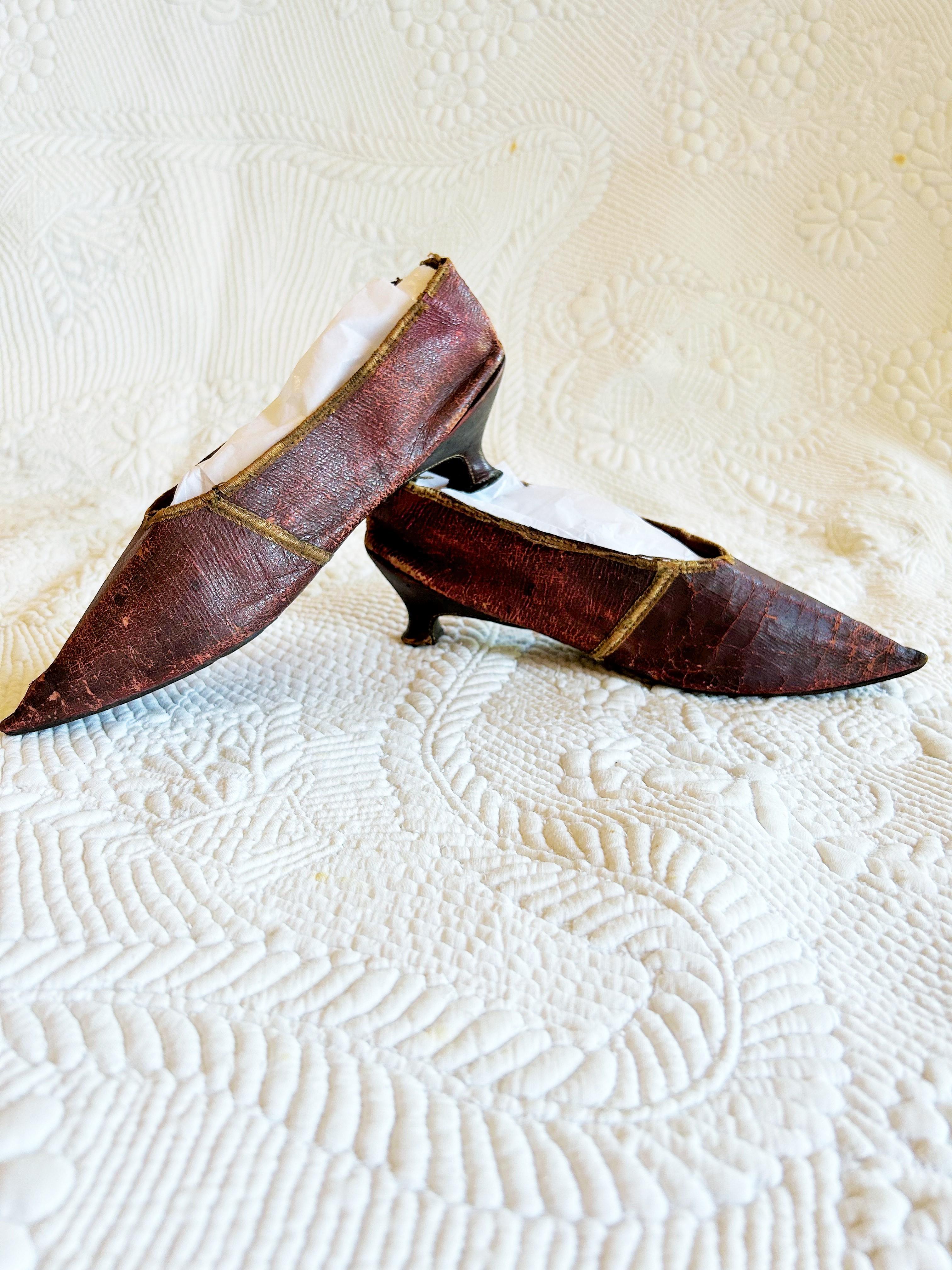 Vers 1790-1800
France ou Europe
Elegante paire de chaussures à talon aiguille en cuir bordeaux datant de la fin du 18e siècle. Empeigne à bout pointu et petit talon bobine, typiques de la mode de l'époque. Doublure en chintz marron clair avec cordon