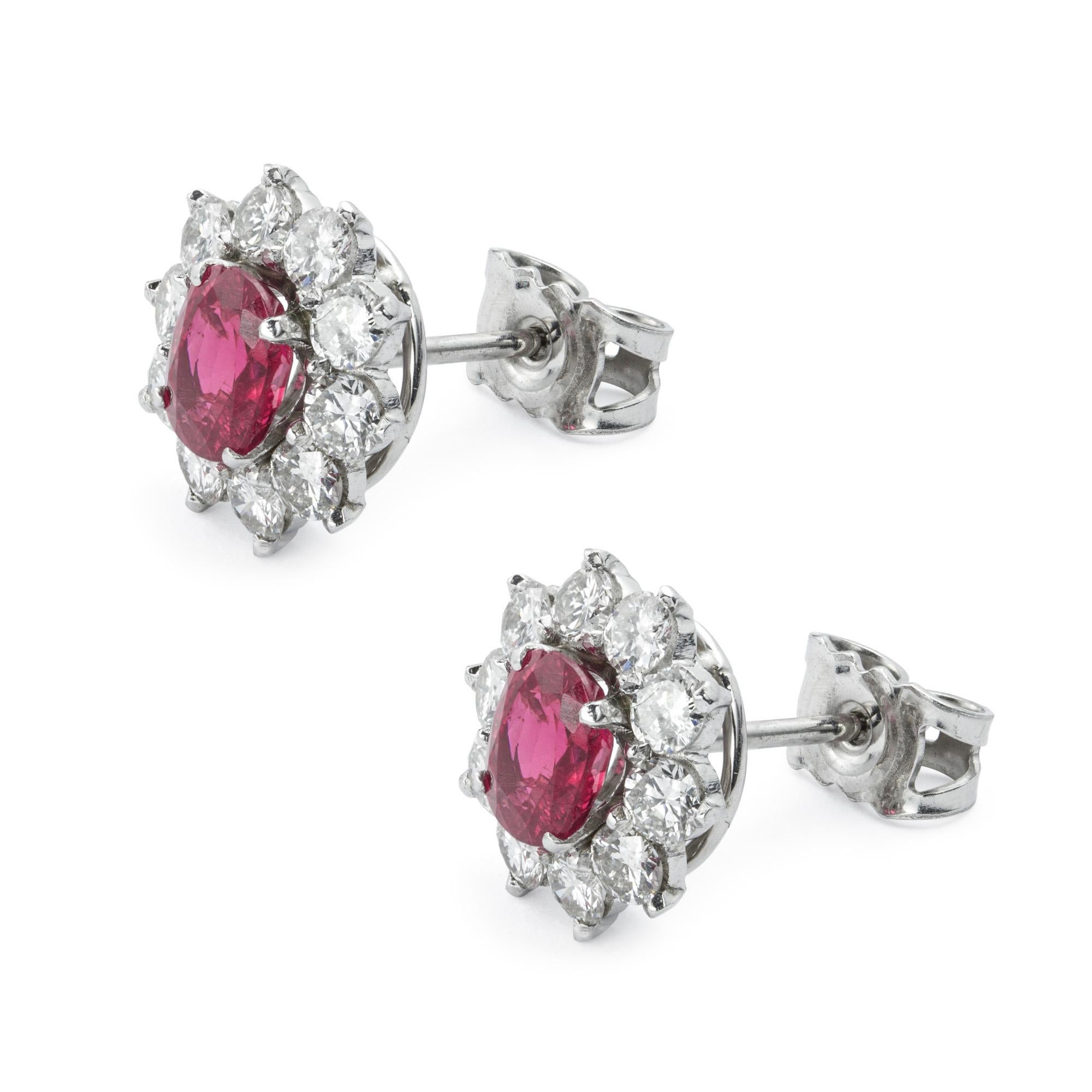 A pair of ruby and diamond cluster stud earrings, each earring consisting of an oval faceted ruby weighing a total of 1.57 carats, accompanied by GCS report no:5777-7872, stating that are of Burmese origins with no indication of heat treatment, set