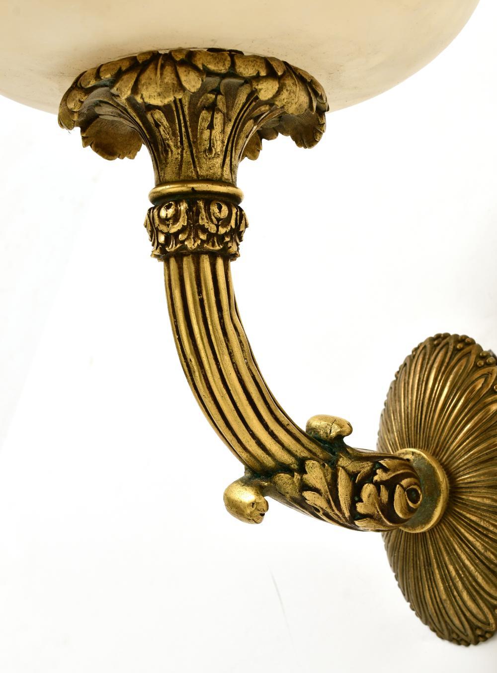 A pair of alabaster Caldwell sconces in a Louis XVI-style design. The curved arms are finely chased with the original signature Caldwell patina. With oval backplates having leaf tip detail and original oversized alabaster shades. Early 20th Century.