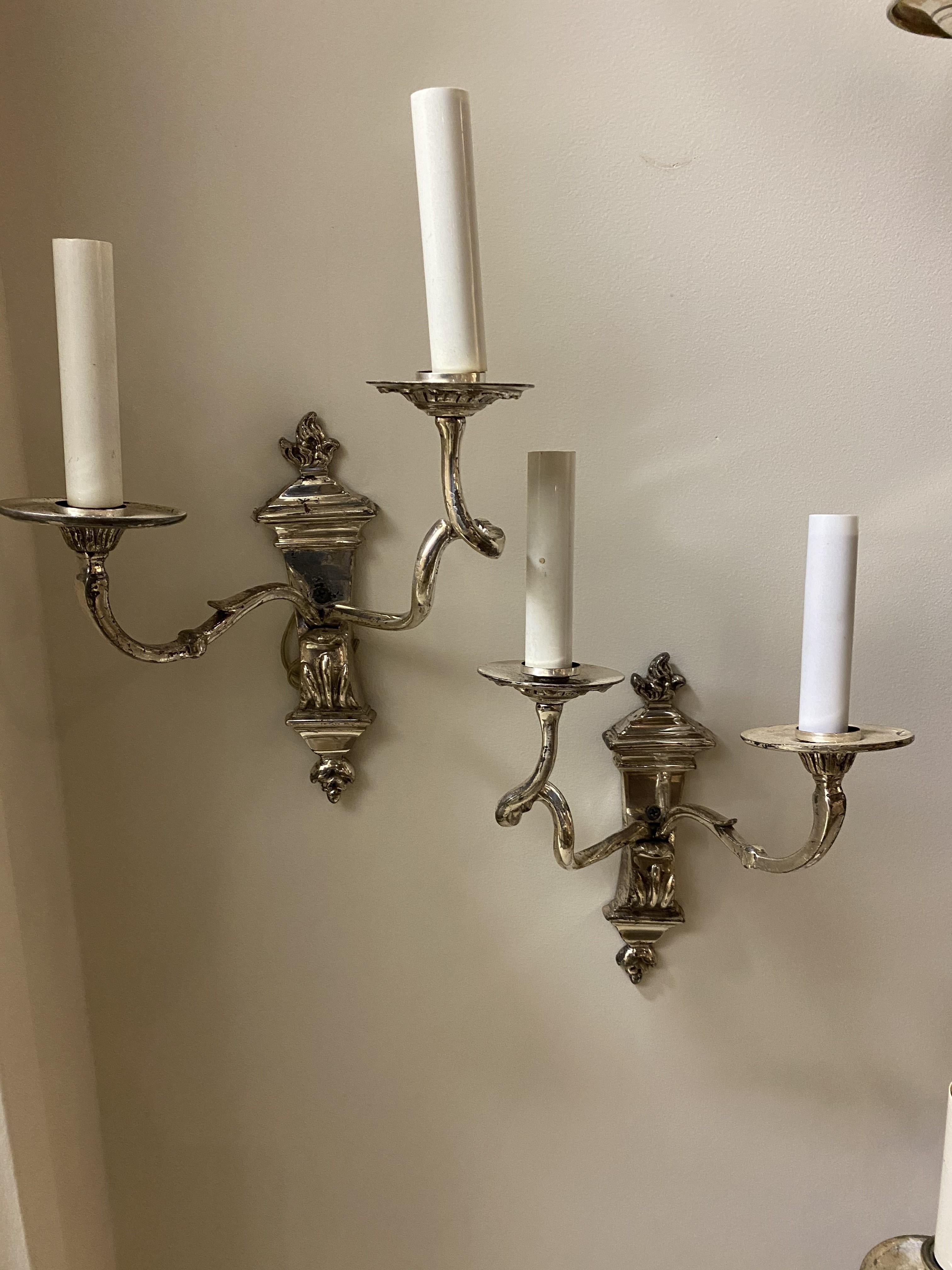 A pair of silver-plated Caldwell double light sconces with scrolled arms.