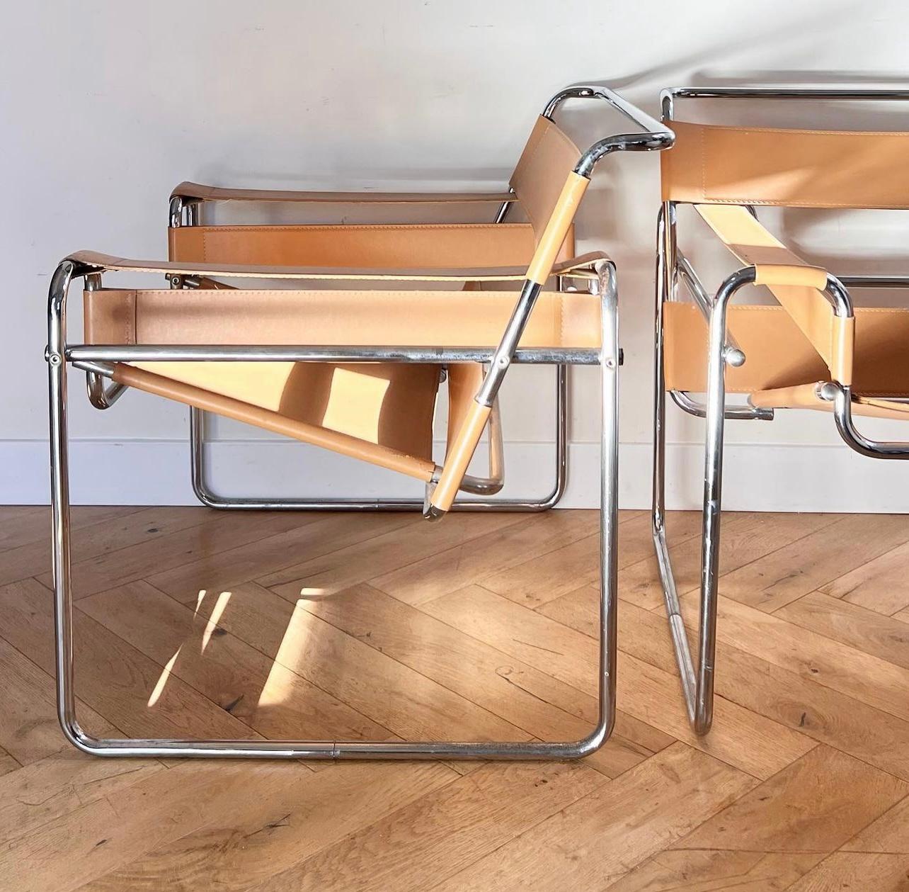 A pair of Marcel Breuer Wassily chairs in camel hued leather, 1970s. Chrome encasings create an architectural framework for the deconstructed parts of this iconic lounge chair. These are high-end reproductions of the original 1920s Bauhaus