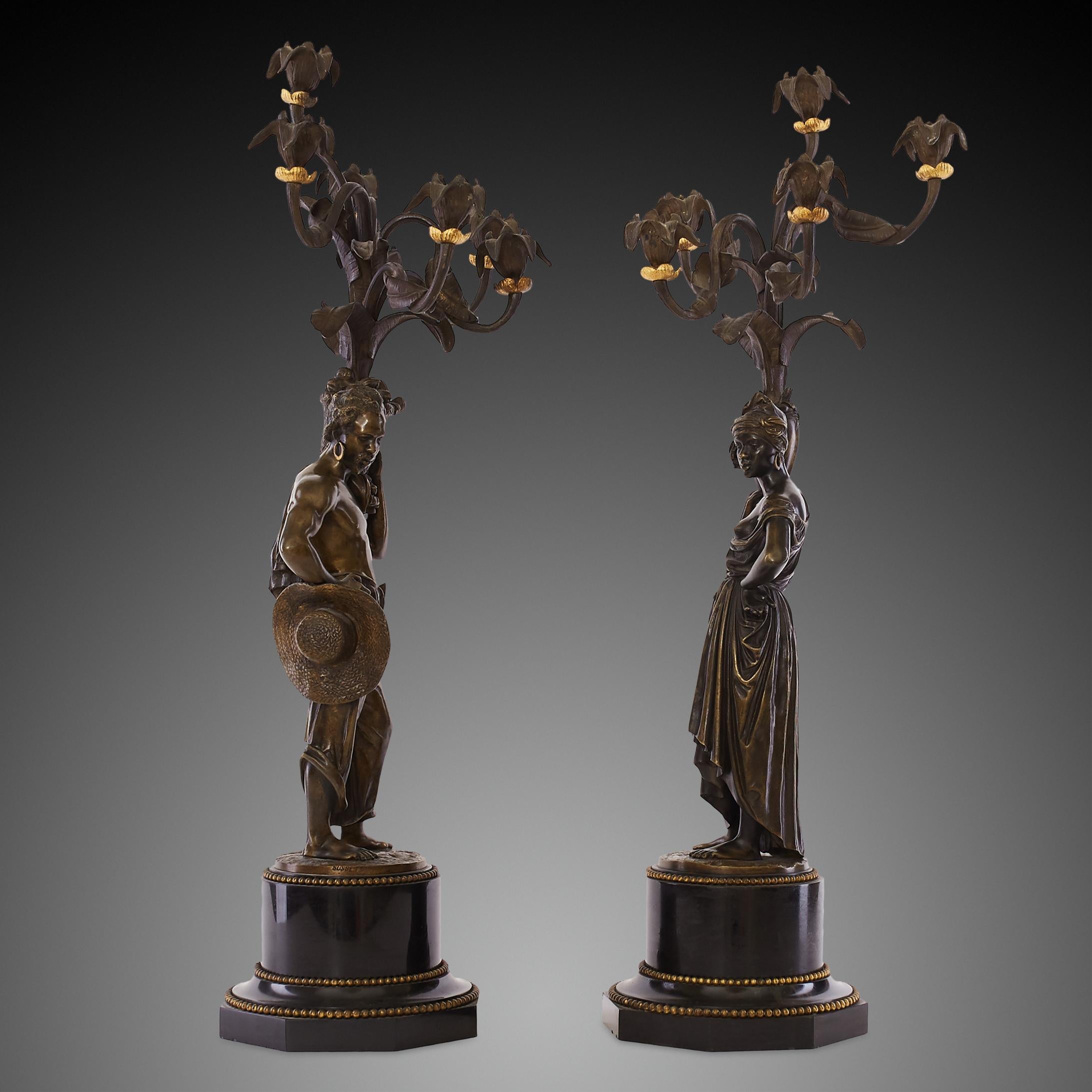 Ces candélabres figuratifs du XIXe siècle, finement moulés en bronze doré et bruni, sont montés sur des socles en marbre noir belge et signés par Charles Cumberworth. Les sculptures ont pour modèle des villageois africains. Le personnage féminin