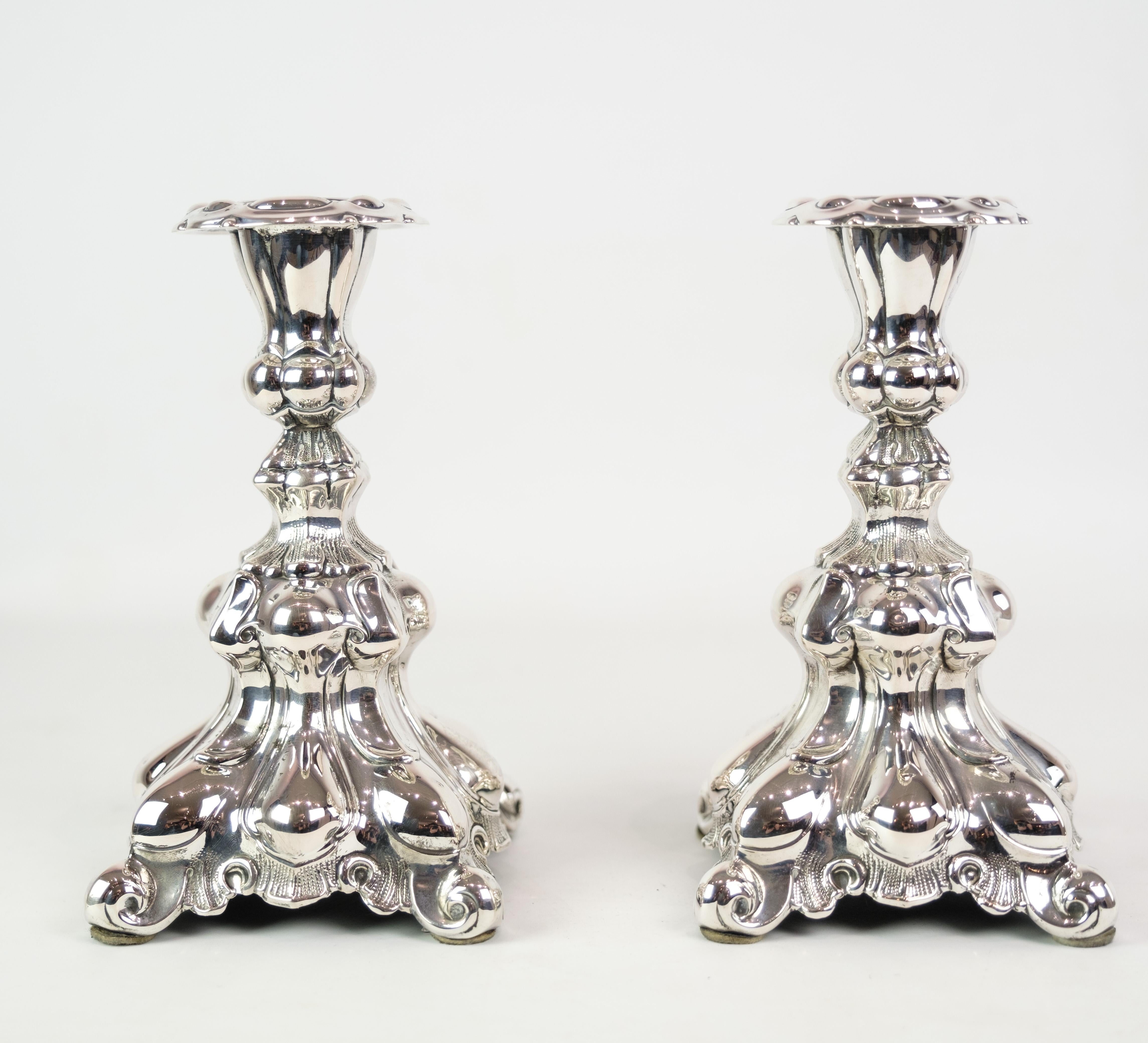 Paire de chandeliers en argent véritable de style rococo, datant des années 1930. Ces chandeliers exsudent l'opulence et les détails complexes caractéristiques de l'ère rococo, ajoutant une touche de grandeur à n'importe quel décor. Grâce à leur