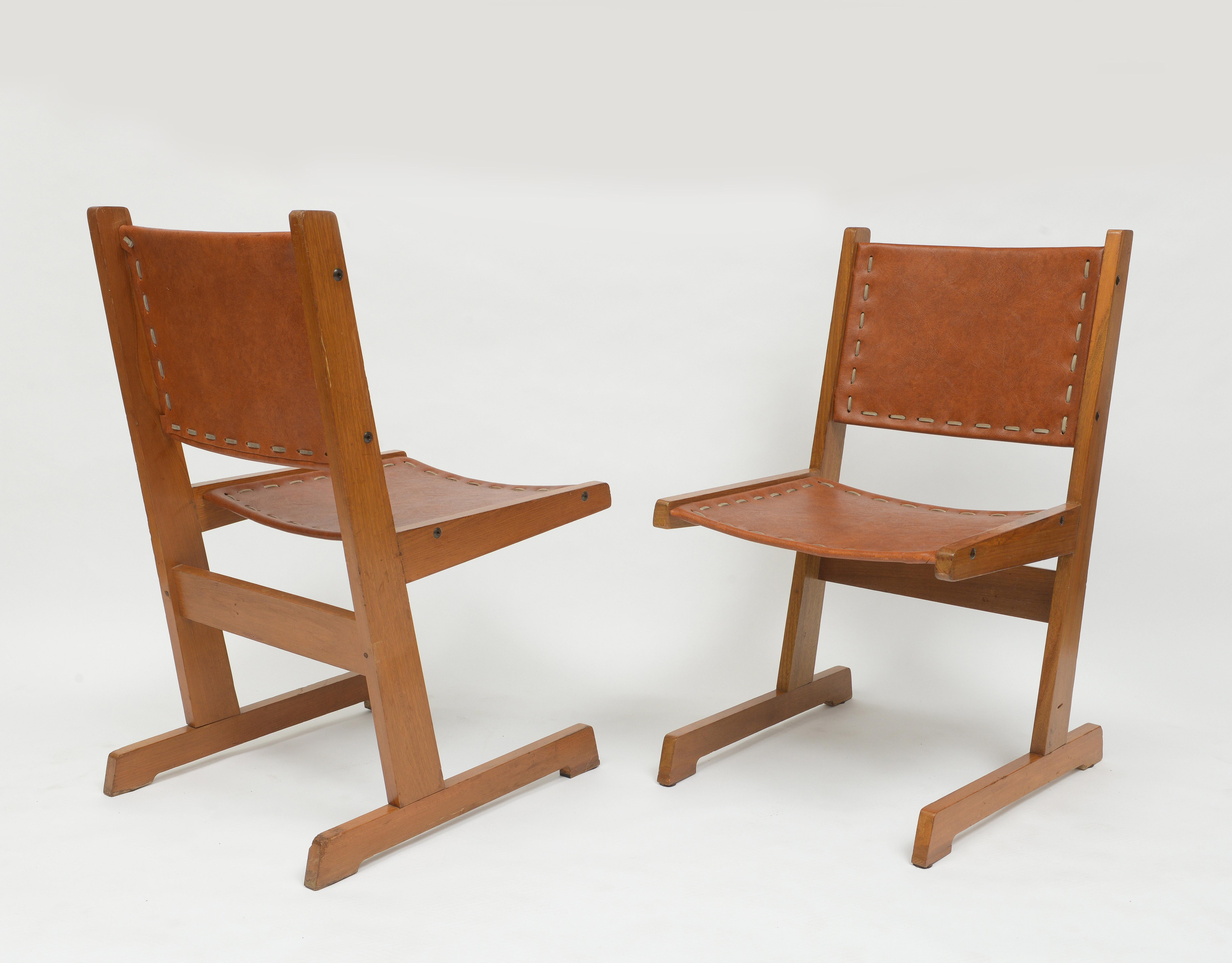 Beautiful pair of hand-stitched leather and wood cantilevered chairs. 