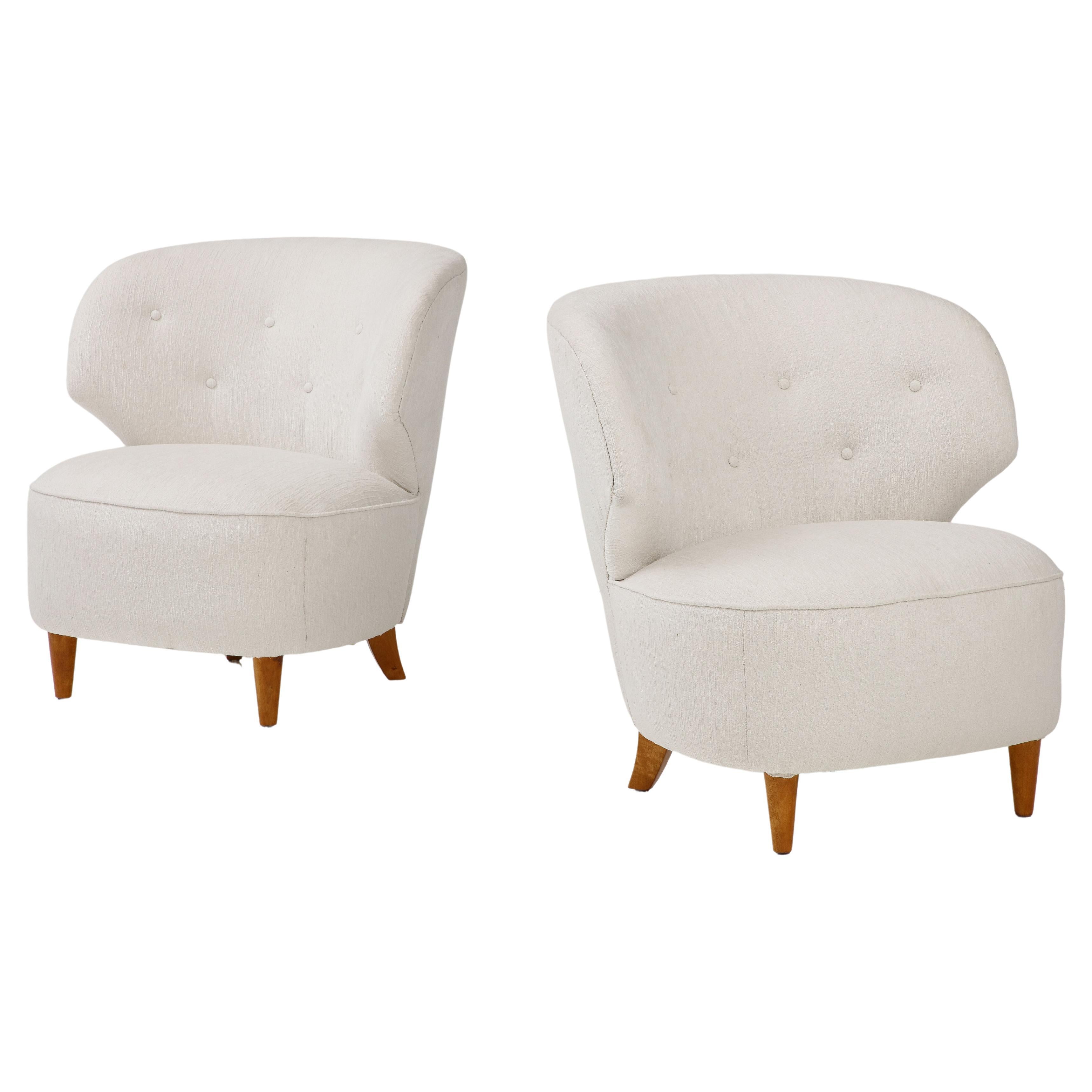 A rare pair of Carl-Johan Boman club chairs, Finland, Circa 1940s, with curved and angular backrests, upholstered rounded seat raised on turned and tapered legs. New white bouclé upholstery. Produced by Oy Boman Ab