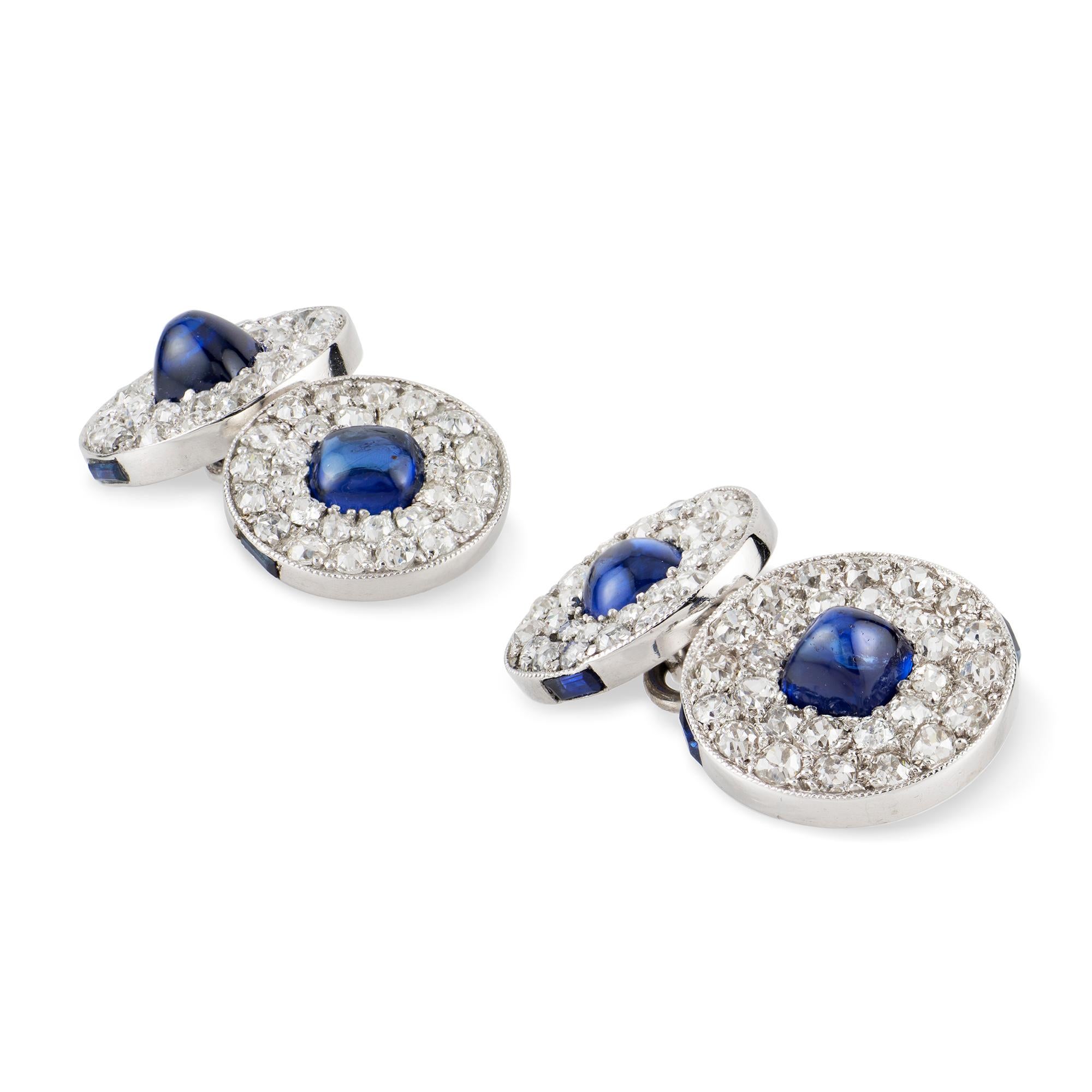 A pair of early 20th century Cartier sapphire and diamond cufflinks, each with a round link centrally set with a sugarloaf-cut sapphire, surrounded by twenty-eight old-cut diamonds, with two rectangular-cut sapphires set on the side, the diamonds