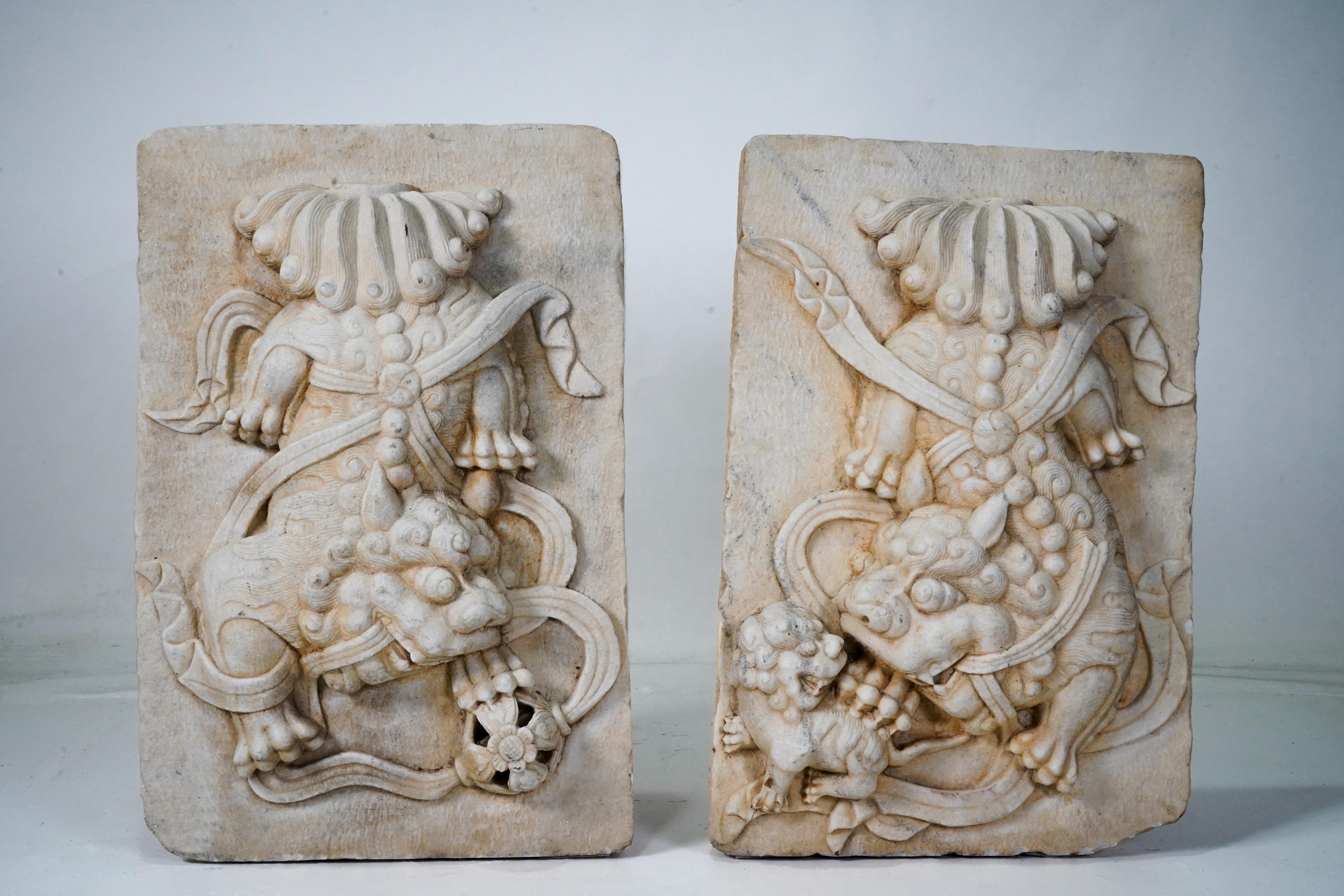 This set of  exquisitely-carved marble garden plaques features two fu dogs playing with ribbons. The female fu dog (or fu lion) guards her pup while the male toys with a ball, which represents the world.   The plaques have a joyful energy that