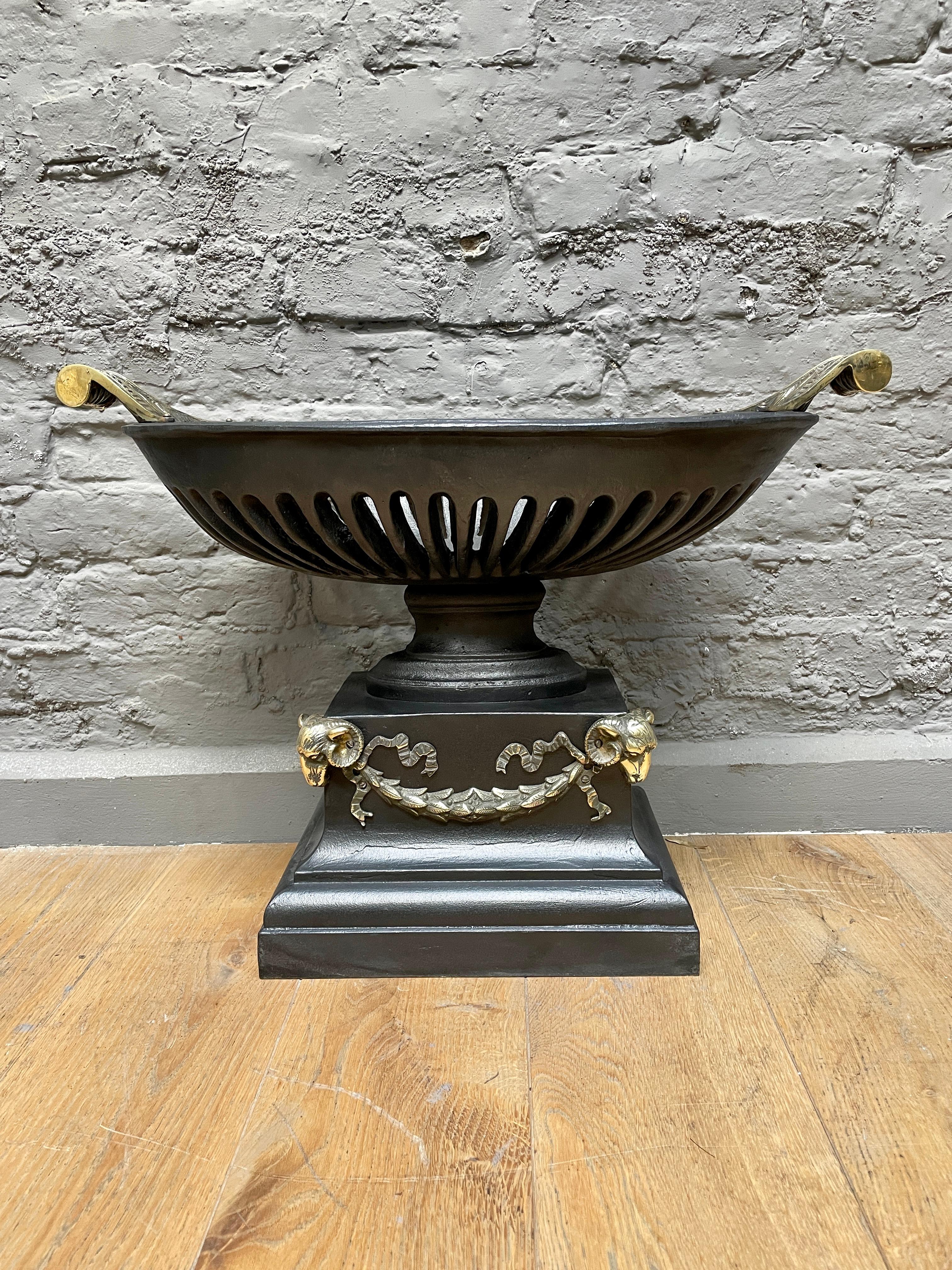 A pair of Regency style Urn grates, in cast iron and brass. The swept and scrolled handles to top of urns, with rams heads and swags to base. A good quality pair of English fire grate circa 1900 in the Regency style 

Can be sold individually.