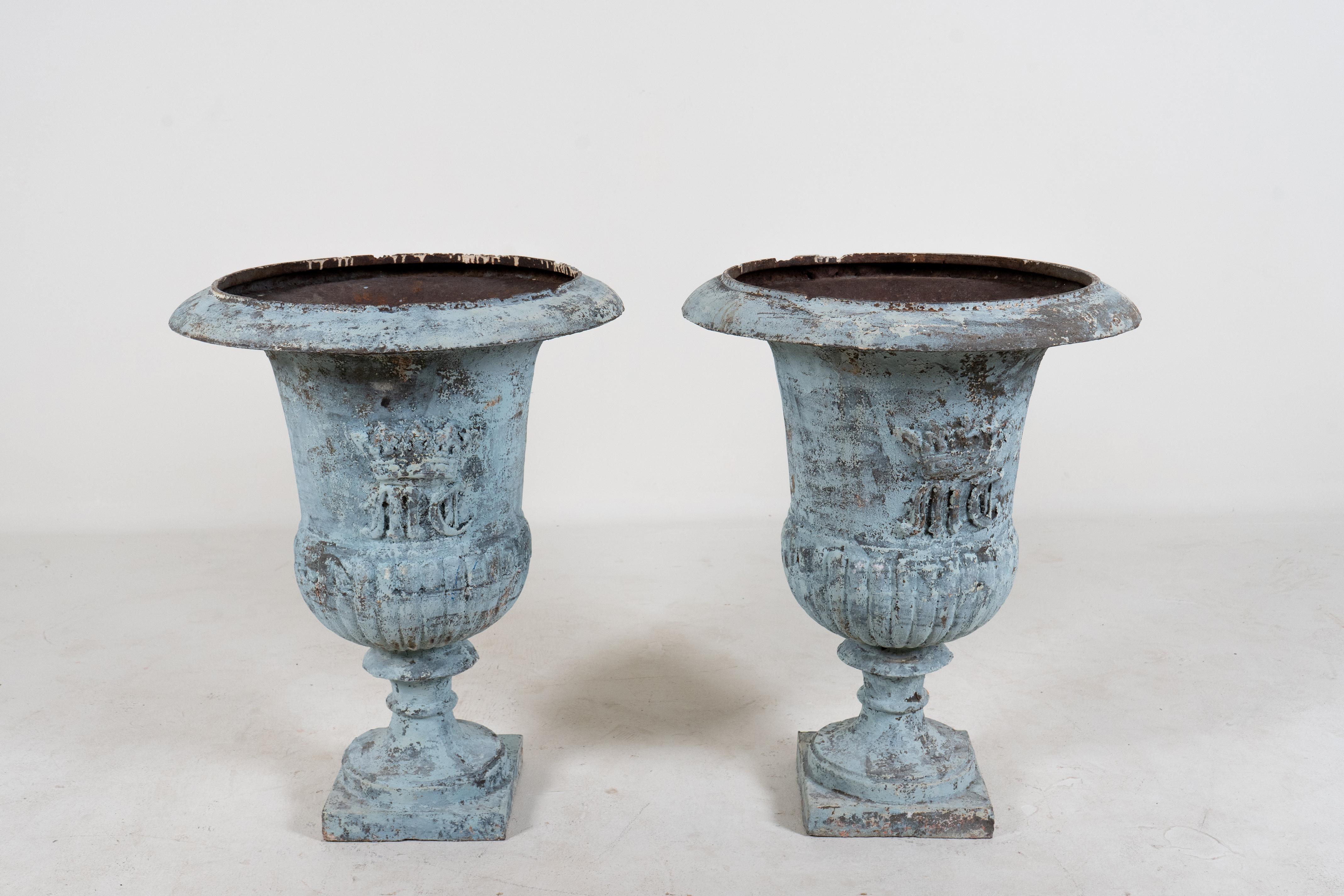 A superb pair of antique French cast iron garden urn planters circa 1900. These elegant campana jardinieres are the quintessential classic French garden urns. While originally used outdoors they can be used indoors as dramatic accessories to