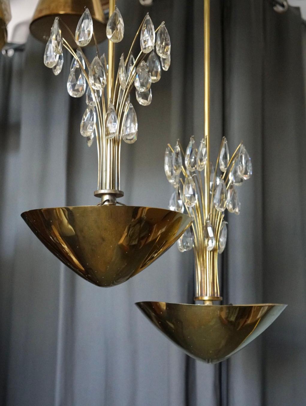 A pair of chandelier designed by Lisa Johansson-Pape for Orno, Finland. Circa 1950th. Perforated polished brass bawl with crystal pendants on stem.
Marked by manufacturer. Existing wires, rewiring available upon request.
 Similar items shown on