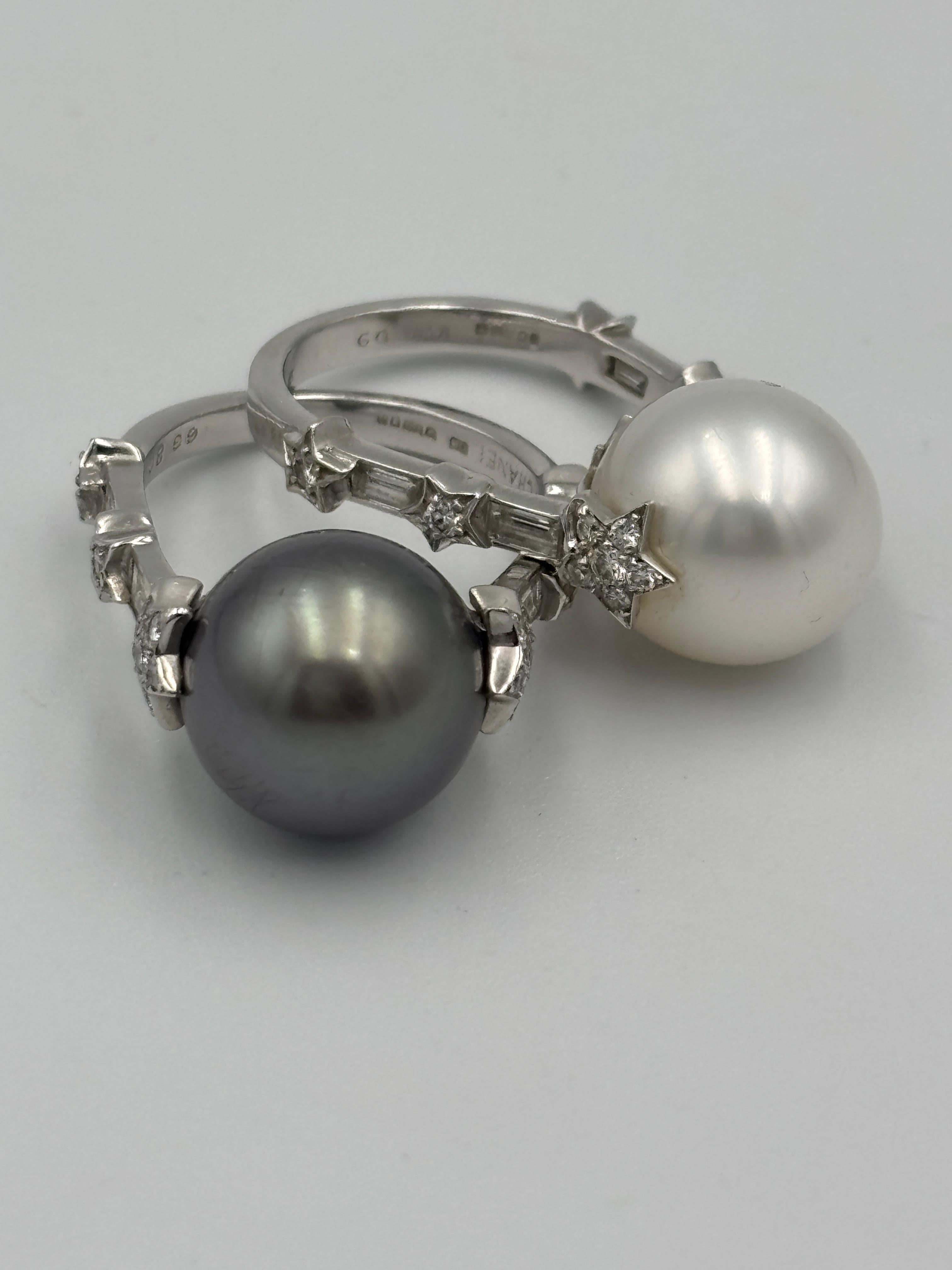 Questi due anelli Chanel degli anni '90 sono venduti in coppia. Uno ha una perla bianca, l'altro una perla grigia, entrambi di 12 mm di diametro. Le perle sono ornate su entrambi i lati da diamanti taglio baguette e tondo incastonati a forma di