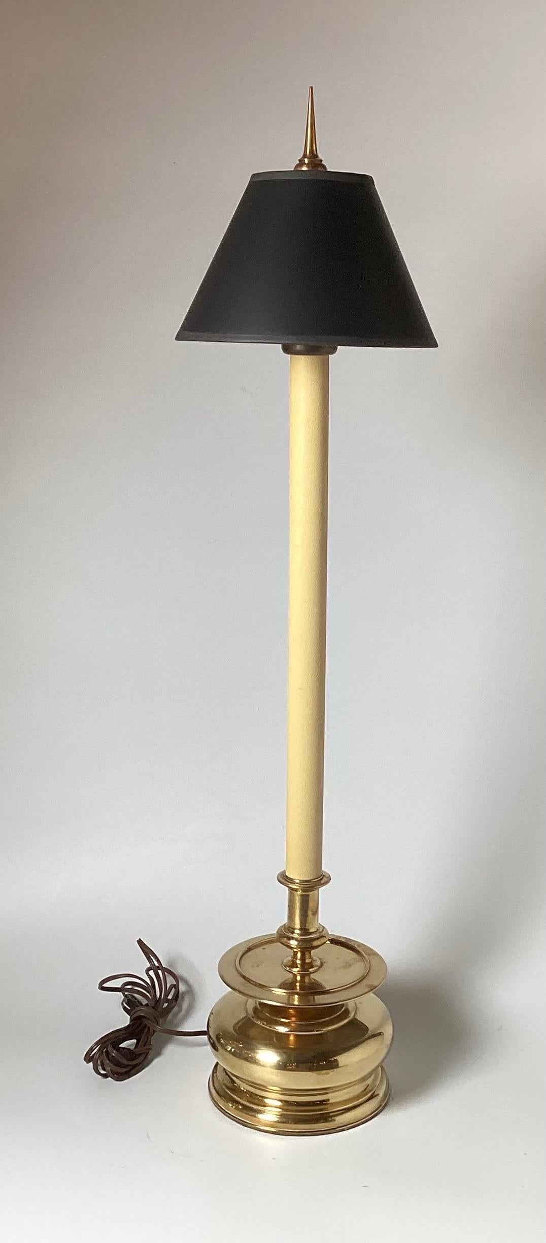 A pair of classic tall Chapman lamps with bulbous cast brass bases with tall central columns with original black parchment shades and point finials.  The lamps measure 37 inches tall to the top of the finial, 29 inches to the top of the sockets, 8