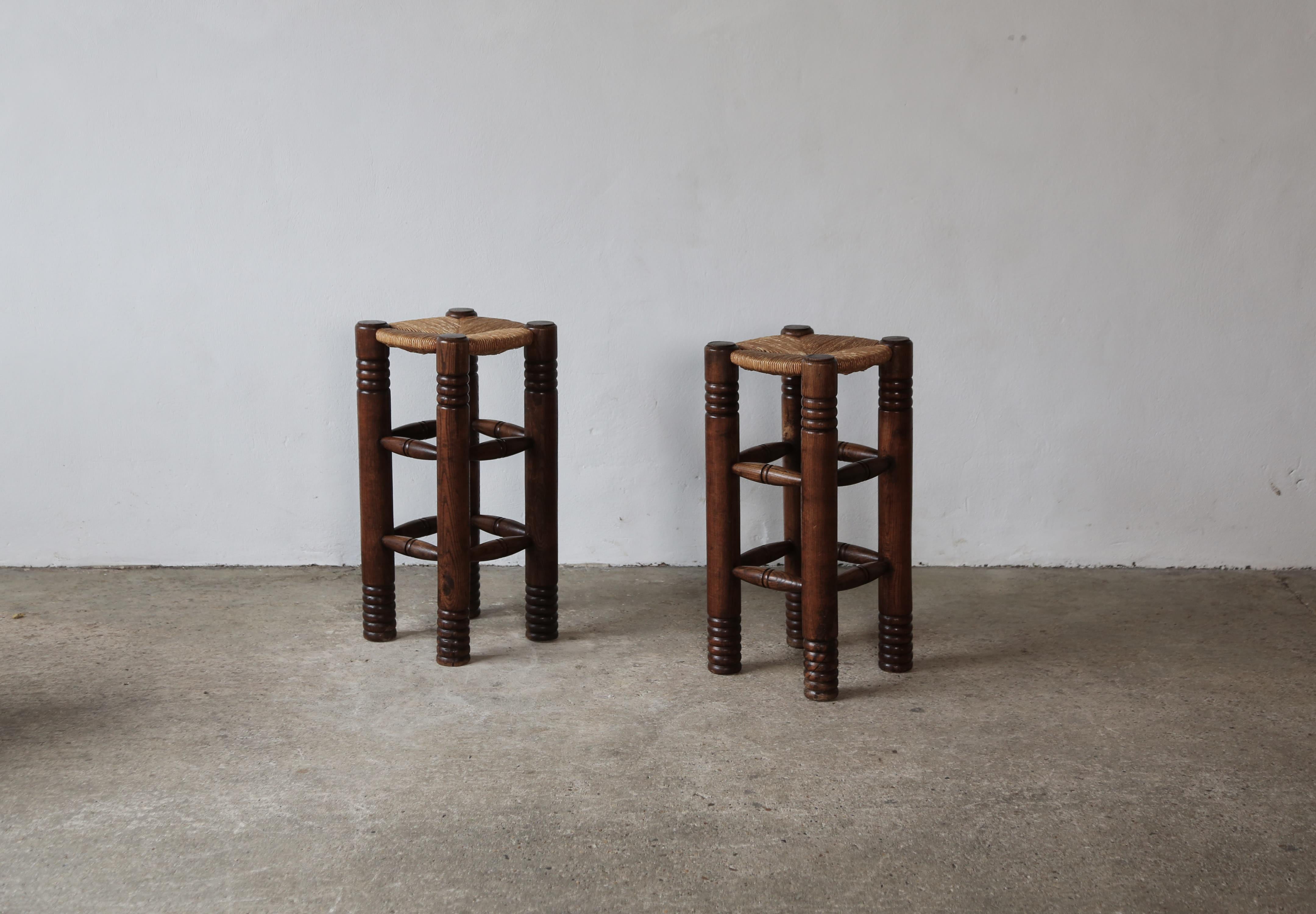 A rare pair of Charles Dudouyt stools, France, 1950s.  The wooden frames in original condition with a nice patina and minor signs of use and wear and minor losses relative to age.  The rush seats are original with no breaks and only minor surface