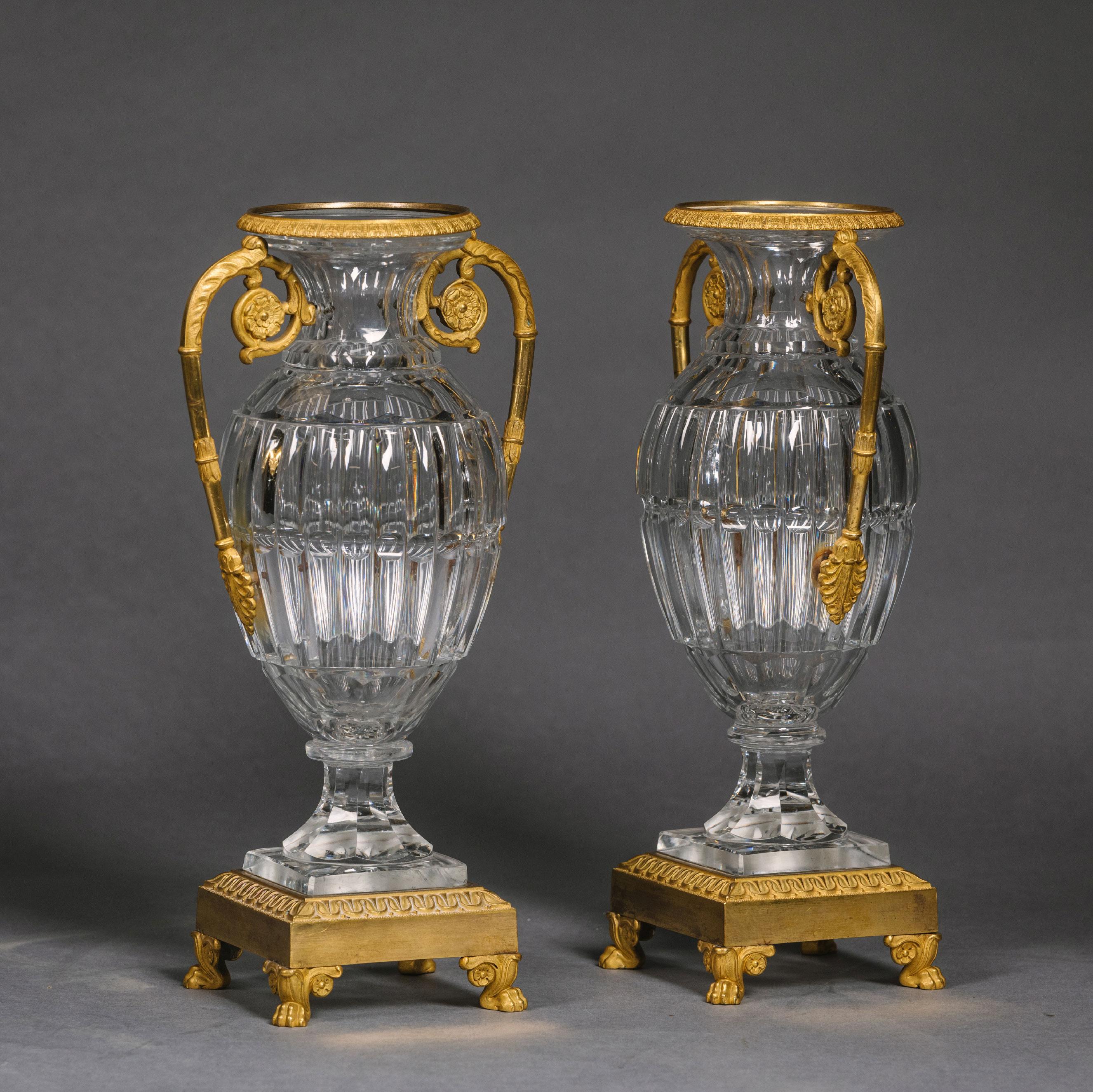 A pair of Charles X gilt-bronze mounted cut crystal glass vases.

Each of ovoid form with ribbed sides, mounted with foliate-scroll handles, on a square leaf-tip base with paw feet.

France. Circa 1830.