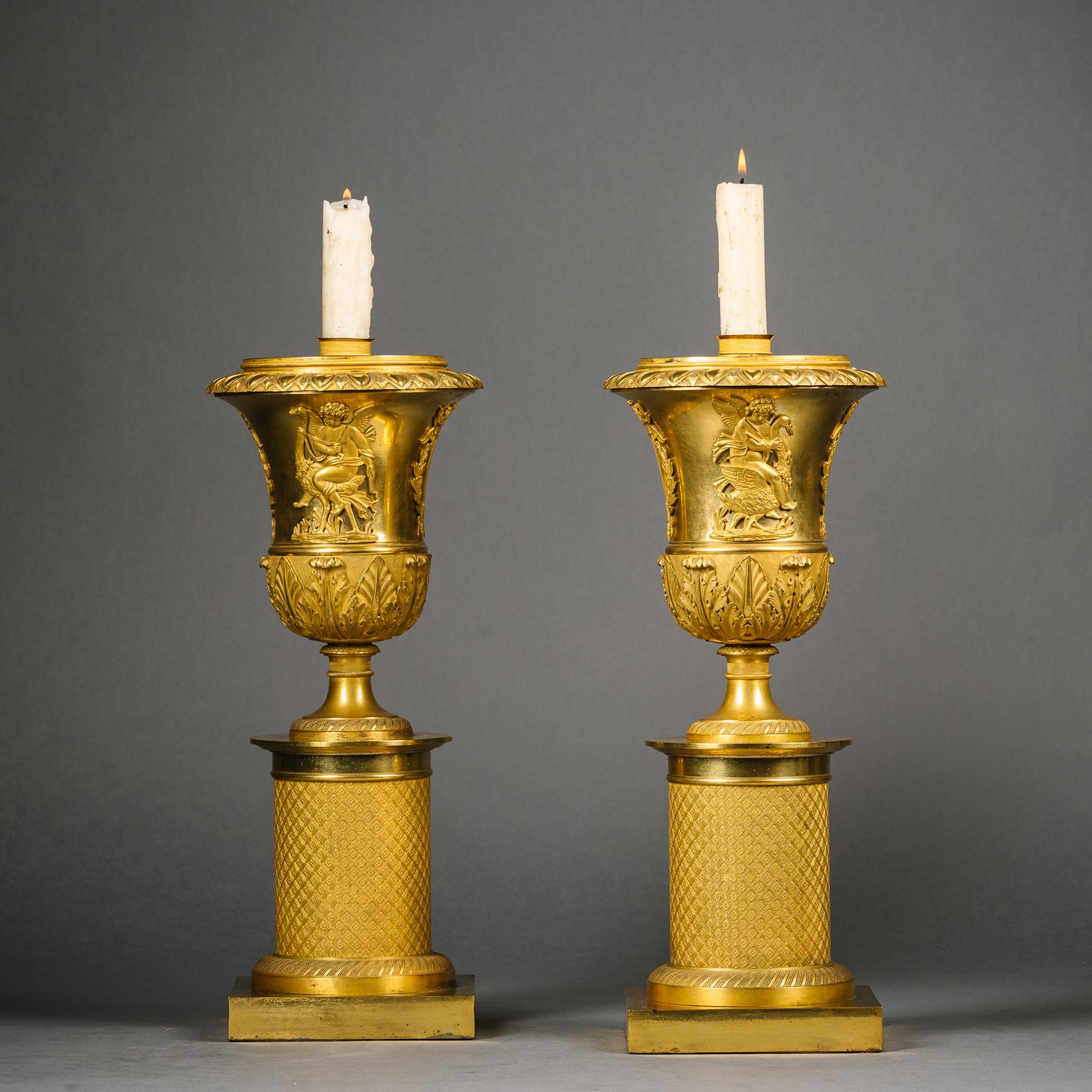 A Pair of Charles X Gilt-Bronze Reversible Cassolettes / Candlesticks 

Each with pierced dome lid surmounted by a butterfly finial. The lids reversible, the undersides fitted with candle nozzles.  The tulip-shaped bodies applied with putti riding