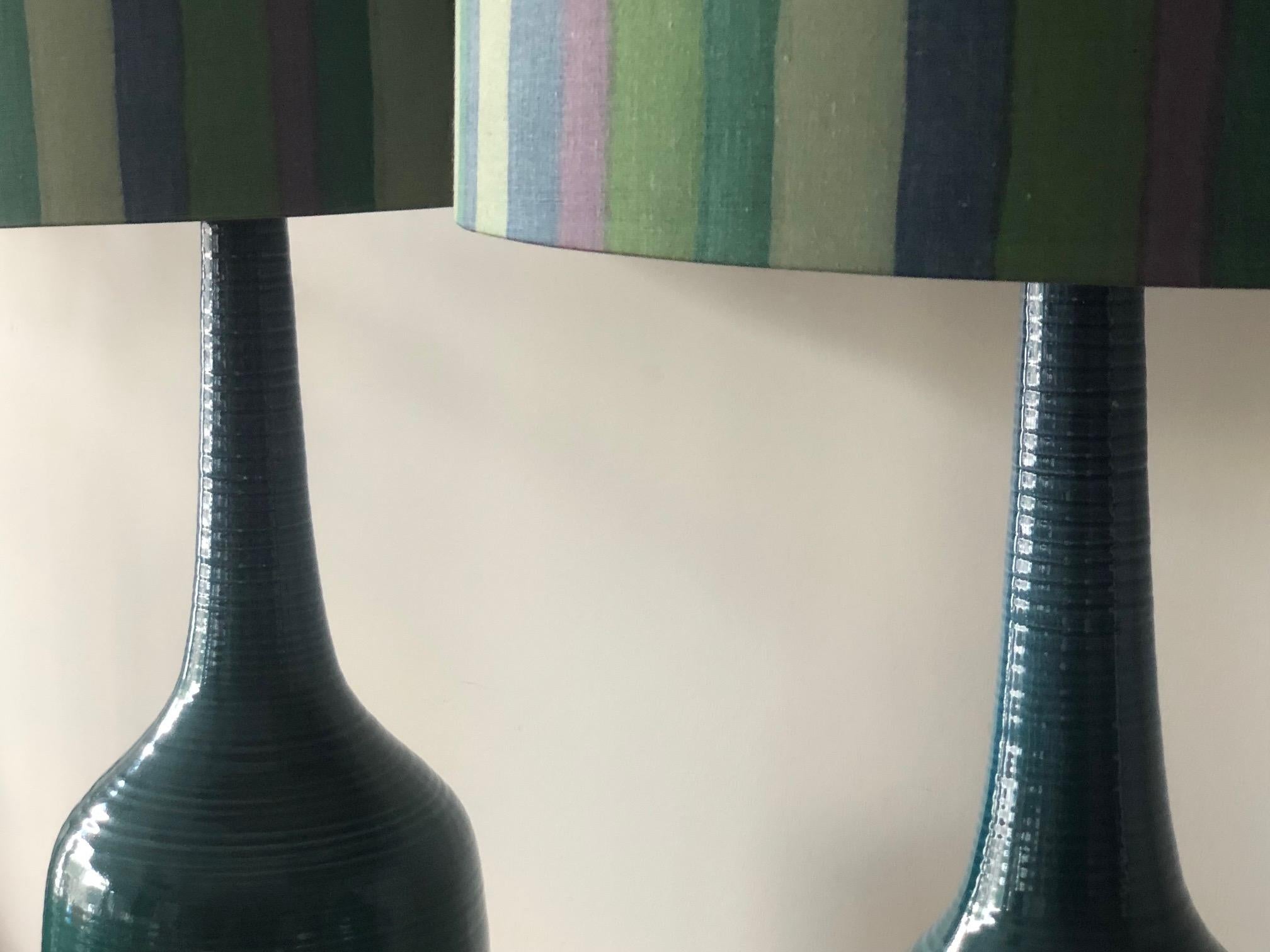 A pair of turquiose ceramic lamps with original striped shades! Greener hue changes to blue towards the top of the lamps, vintage circa 1960s. Total height with shades 40