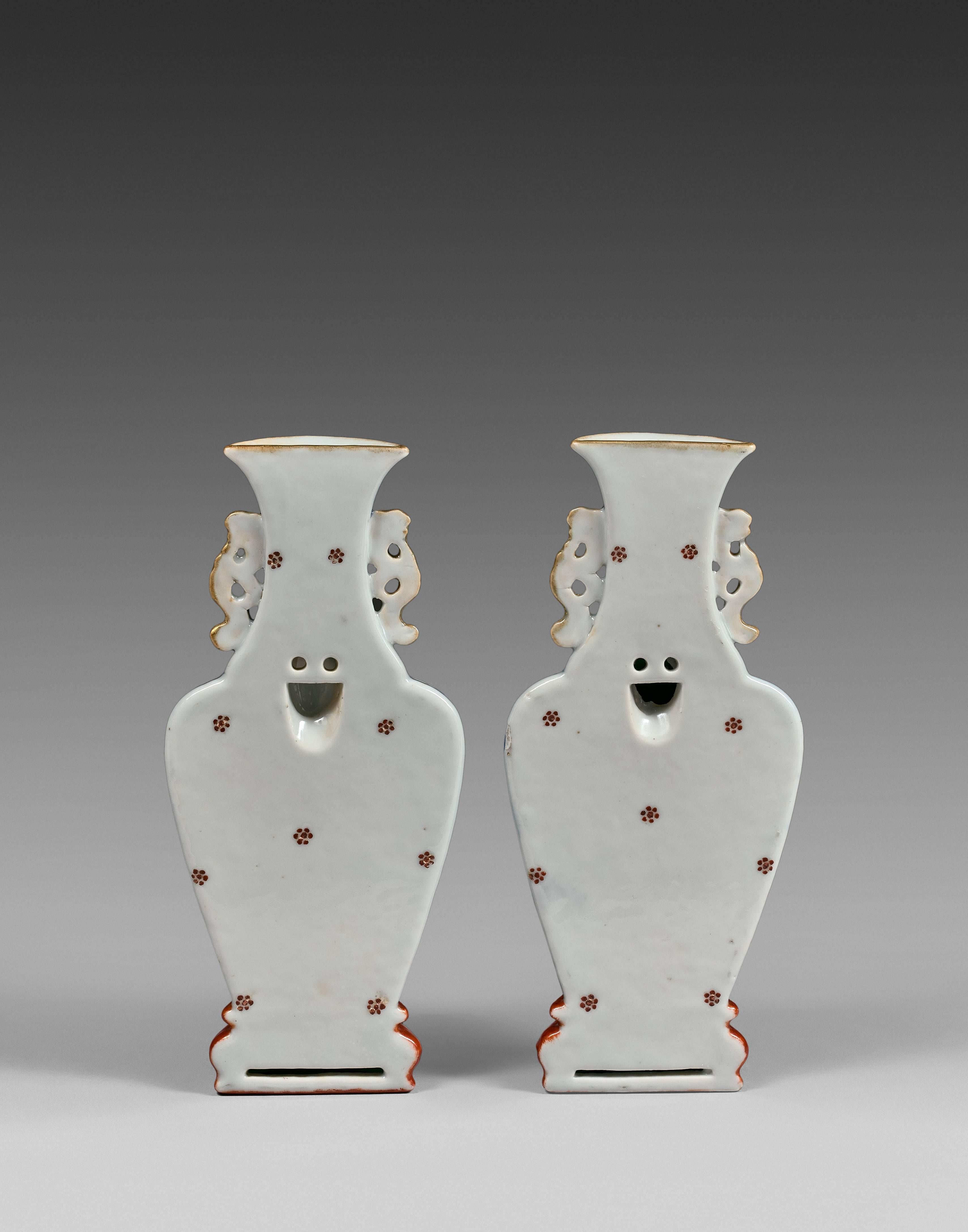 Each vase flattened at the back, the body sweeping up from a short splayed foot to a broad shoulder and waisted neck, the neck flanked by a pair of archaistic scroll handles, all resting on a trompe l'oeil faux-bois stand, the body and neck