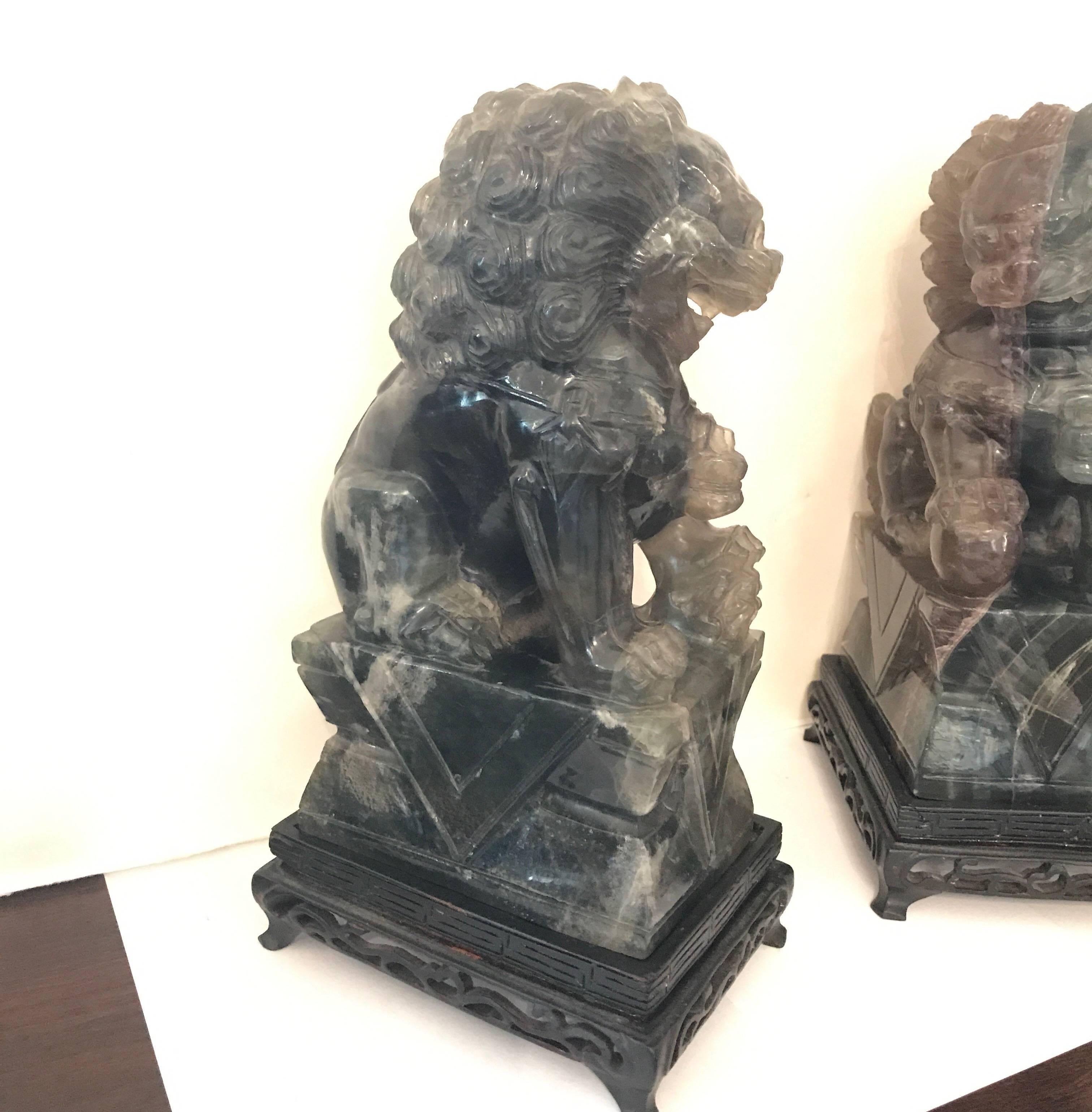 A pair of carved green quartz foo dogs with wood bases. The original pair, one male, one female in a darker variegated quartz, circa 1920.