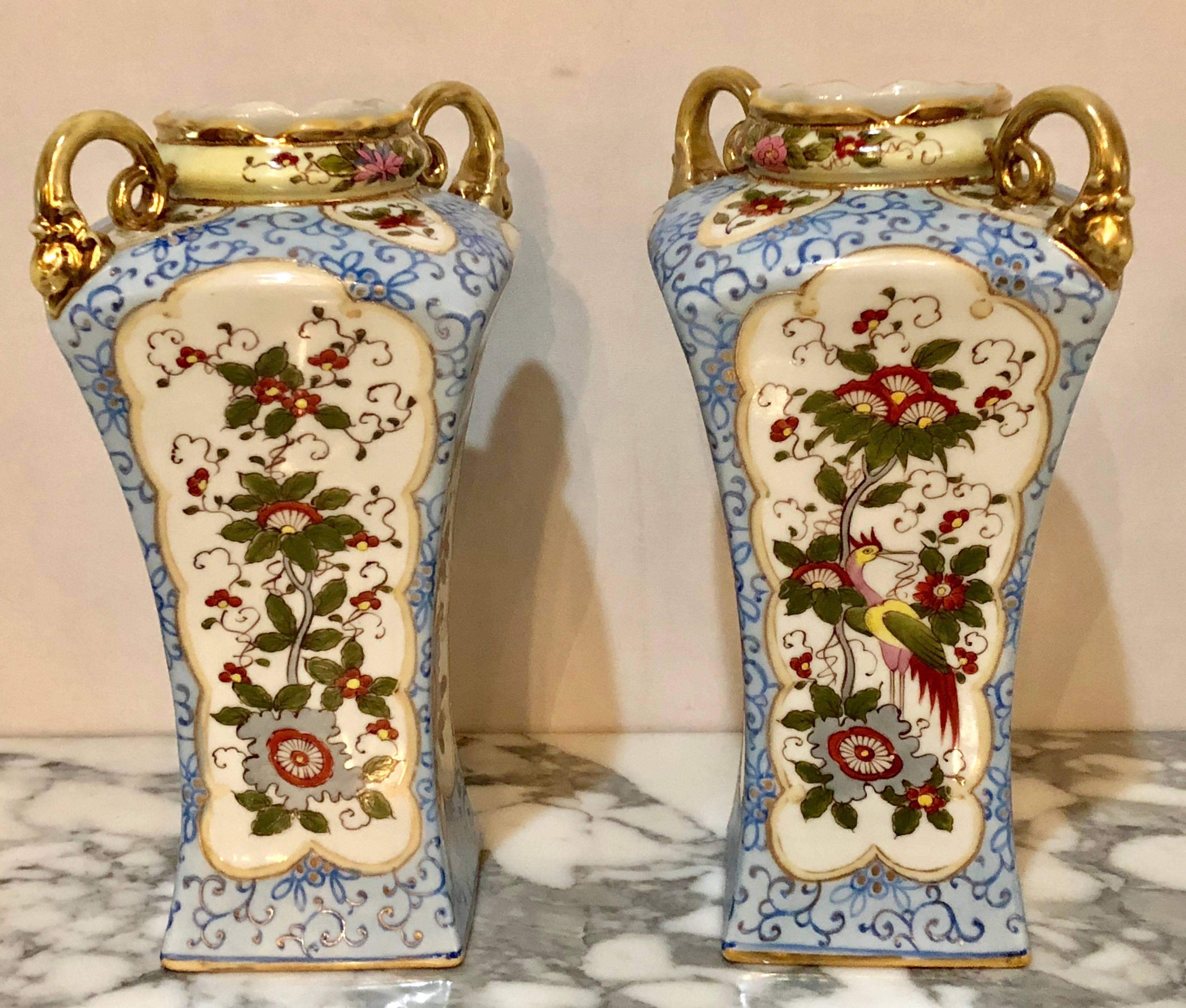 A pair of Chinese Chippendale style twin handled Nippon vases. Each of these hand-painted vases have gilt gold handles, rims and bases as well as framing to separate the finely cast design on these highly decorative and collectable vases. The pair