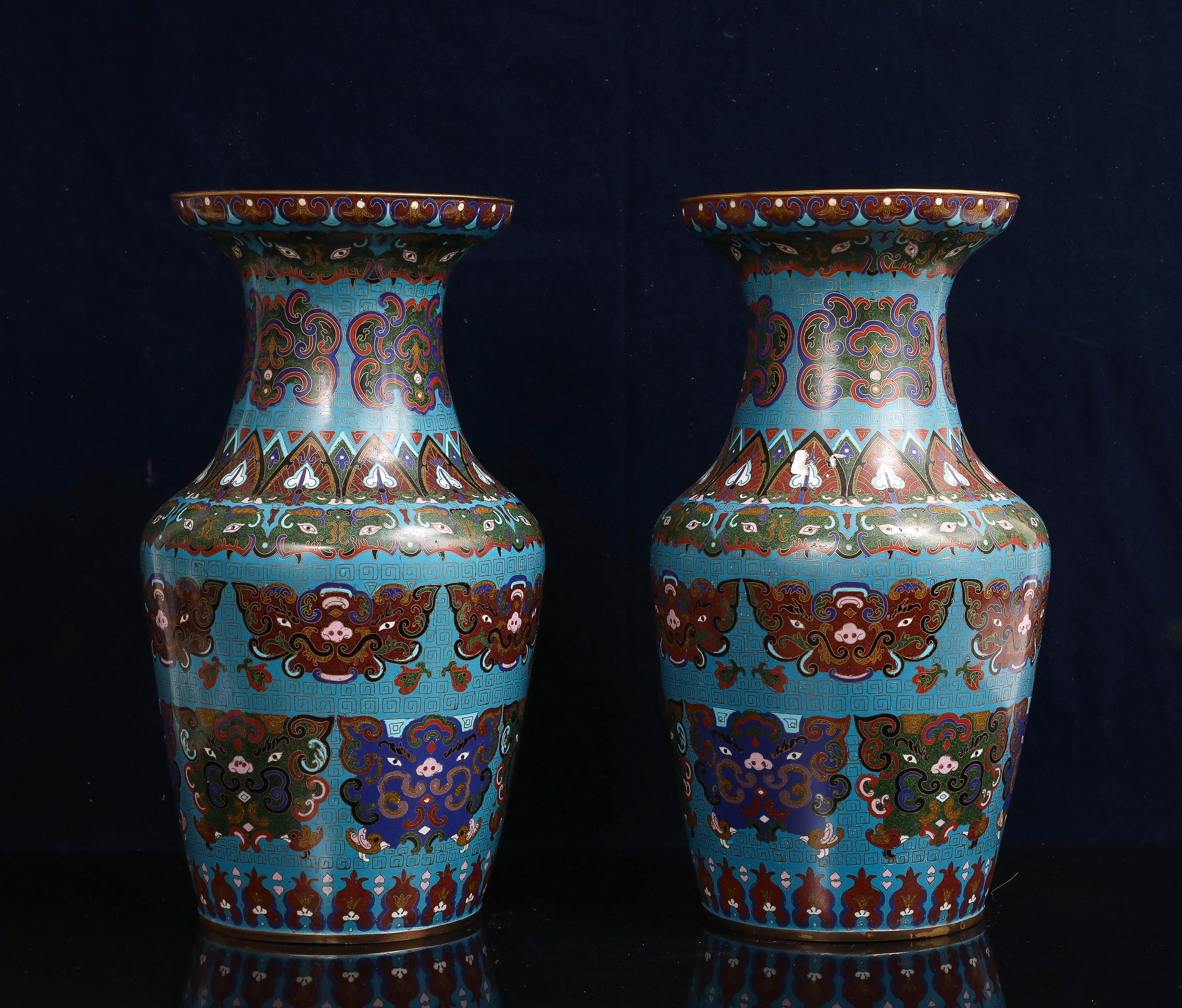 Coppia di vasi cinesi in smalto cloisonné con fondo blu turchese e decorazione a maschera taotie, inizio XX secolo. I vasi sono costruiti a forma di balaustro con ampi bordi svasati e presentano una caratteristica lavorazione cloisonné con smalti