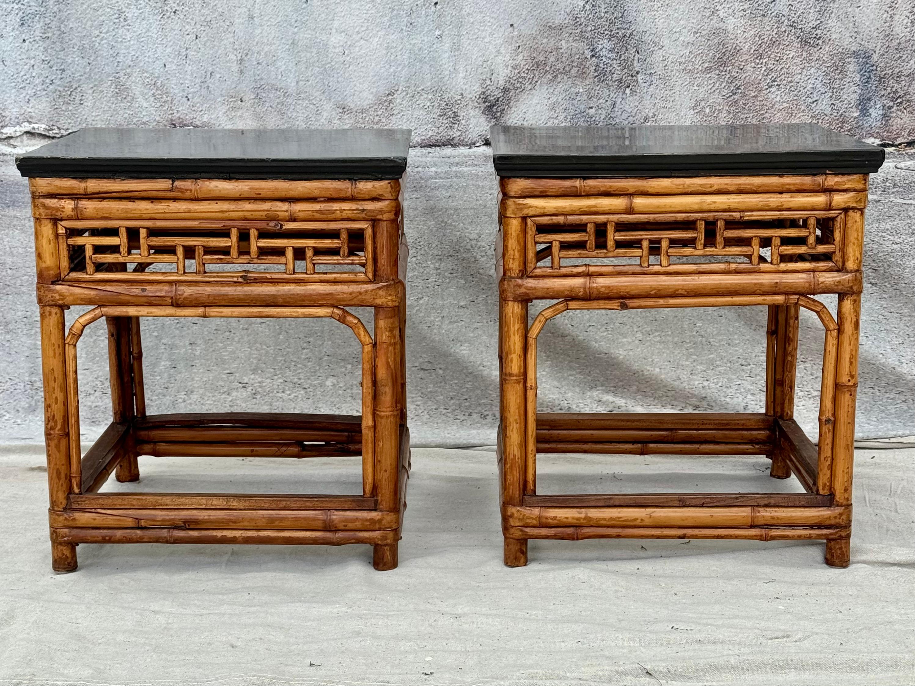 An amazing pair of McGuire style Chinese export ebonized top bamboo side tables. Tables have intricate geometric bamboo open fretwork decoration and are topped with square black wood tops supported by round bamboo legs. 