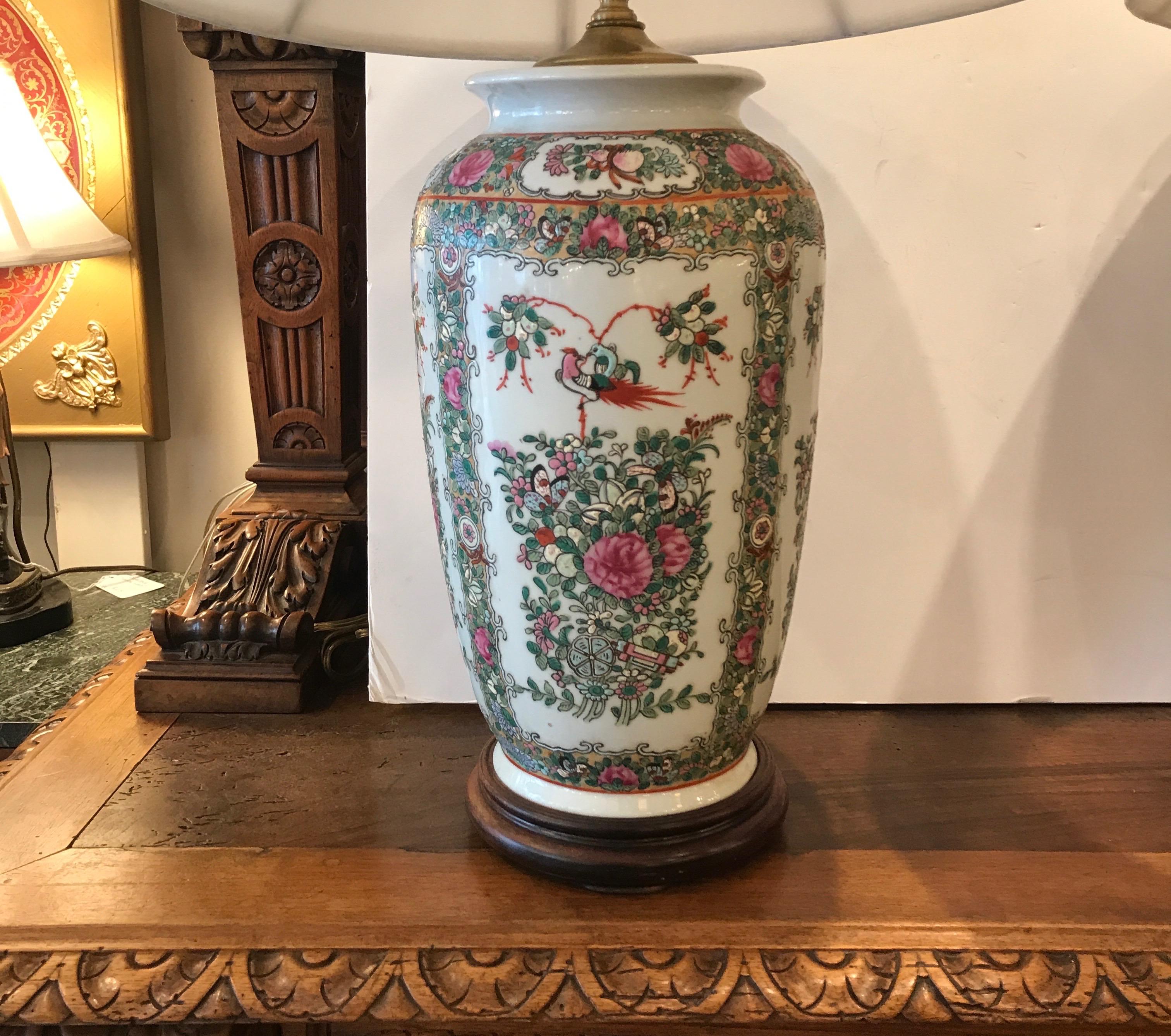 A pair of hand painted Chinese porcelain lamps with simple carved wood bases. These are in a classic Rose Medallion pattern. The wiring is in great condition and ready to use. The shades are for photographic purposes only and not included. Height