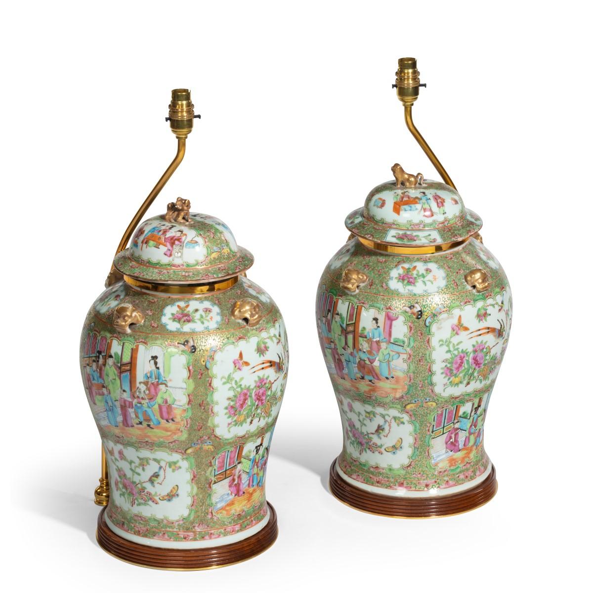 A pair of Chinese vases and covers, each of baluster form with a domed cover and a stylized gilt Fo-dog finial and handles, decorated in colored enamels and gilt with numerous panels showing courtly scenes, birds and butterflies amongst flowering