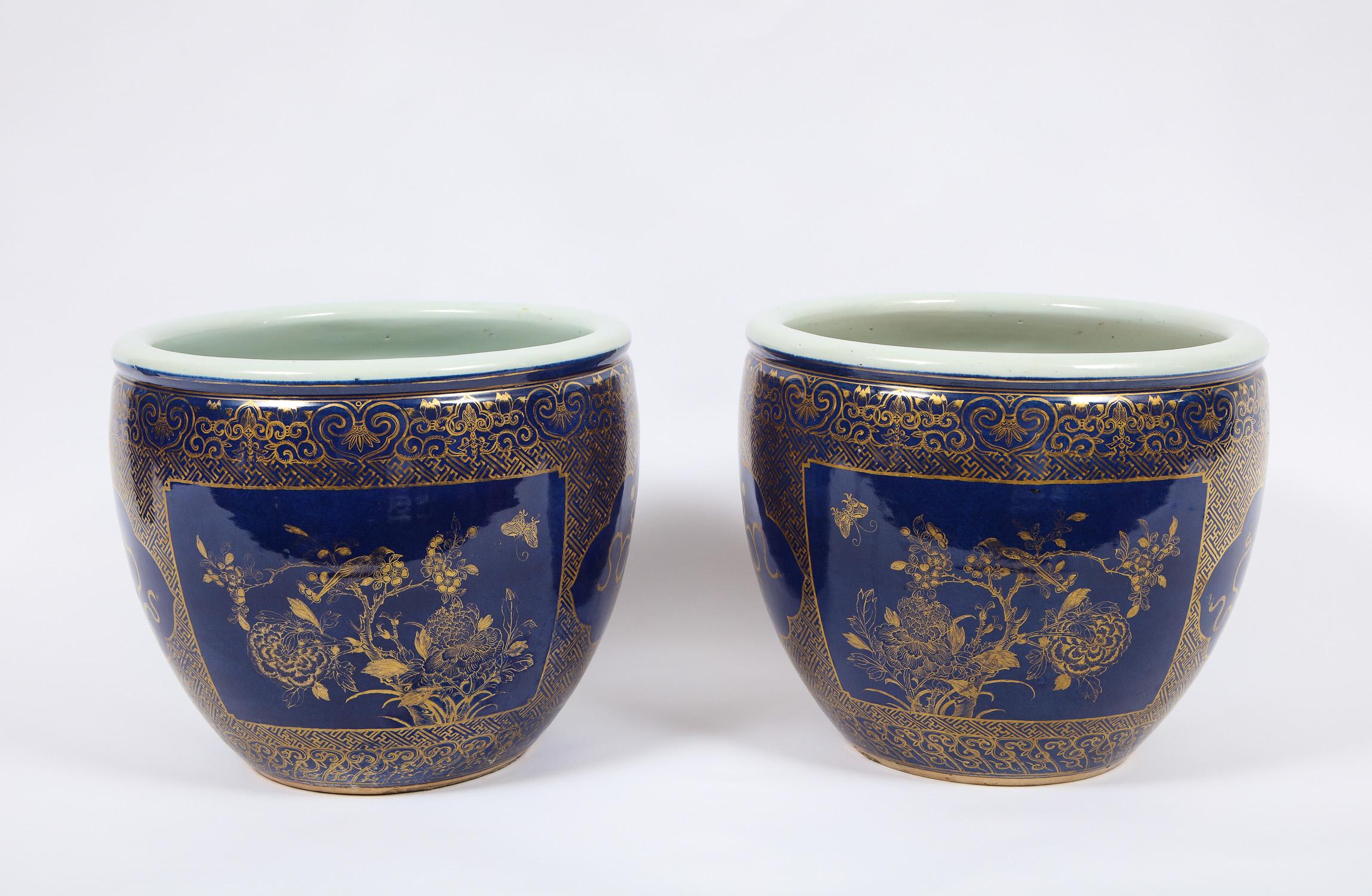 A magnificent pair of Louis XVI style Chinese porcelain bleu poudre and 24-karat gilt decoration fish bowls/jardinieres. Each is beautifully hand painted and further decorated in brushed 24-karat gilding. Four mirror image cartouches are found on