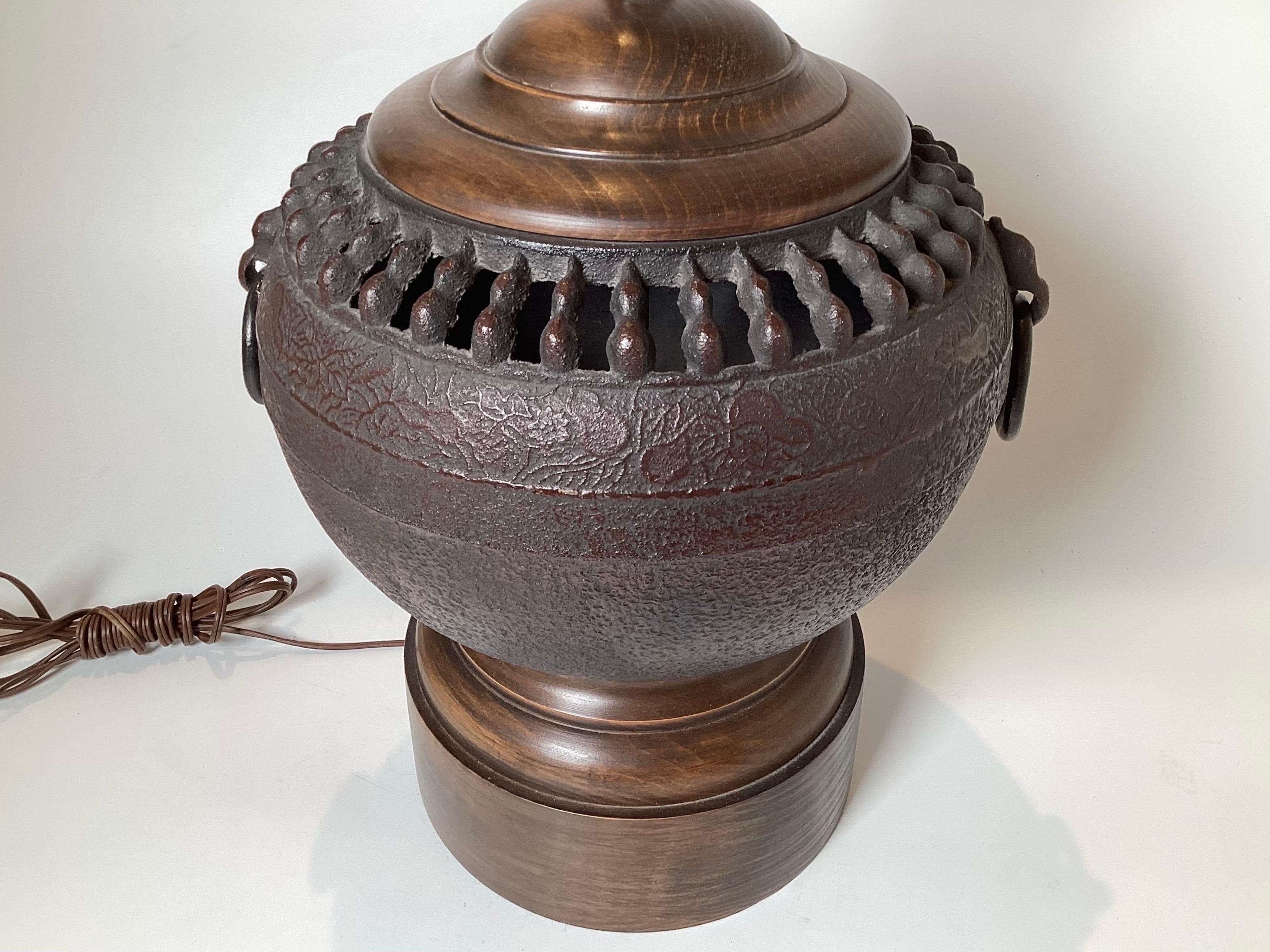 A Pair of Chinese style urn form lamps with wood bases.  The patinated bronze on medium stained hardwood bases, 13 inches in diameter, 21 inches to the top of the socket, with a shade would be around 30 inches tall 