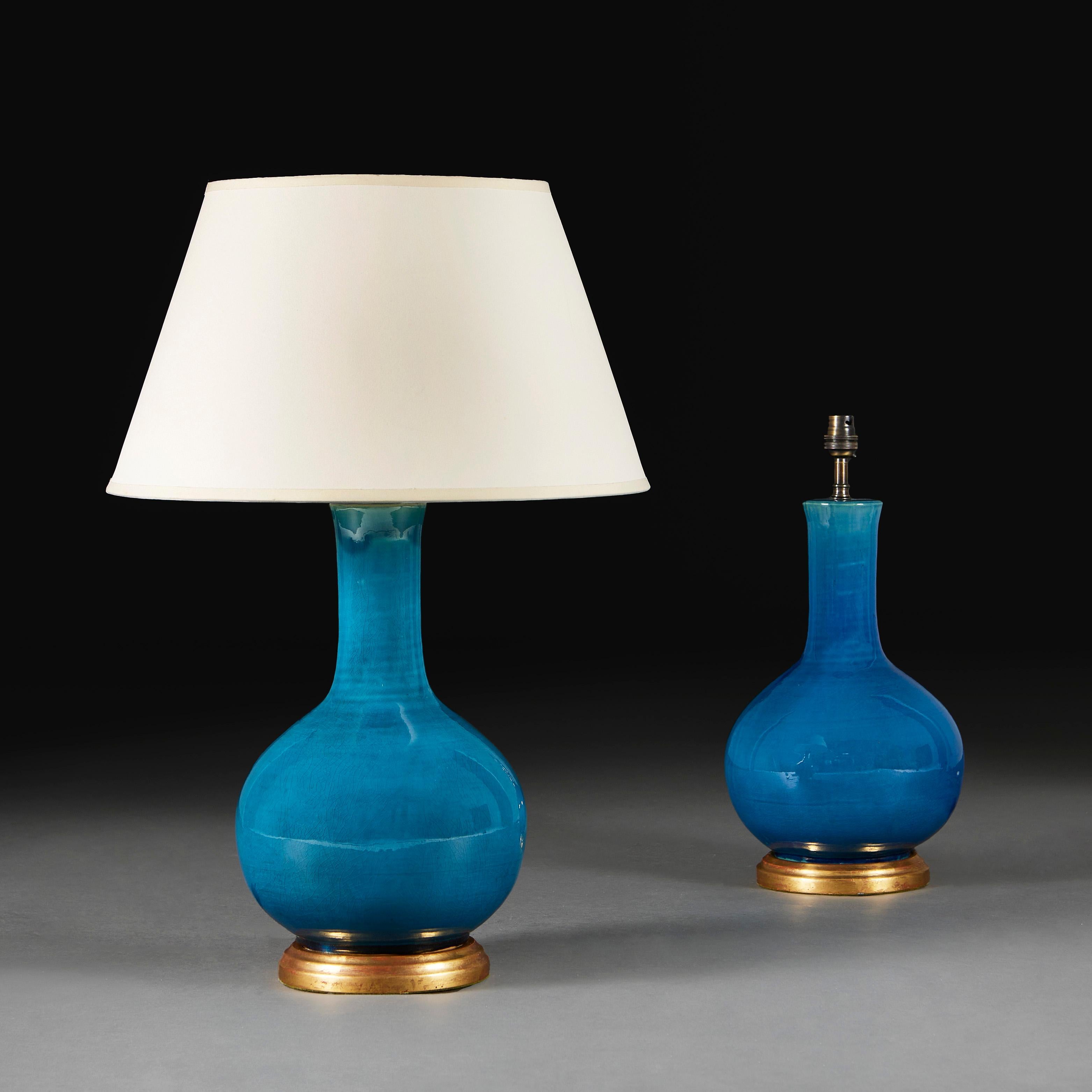 A pair of early twentieth century Chinese vases with brilliant turquoise glaze, of bottle form, now mounted as lamps with turned giltwood bases.

Please note:
Lamps have been photographed with a 16” pale cream Pembroke card lampshade.
Currently