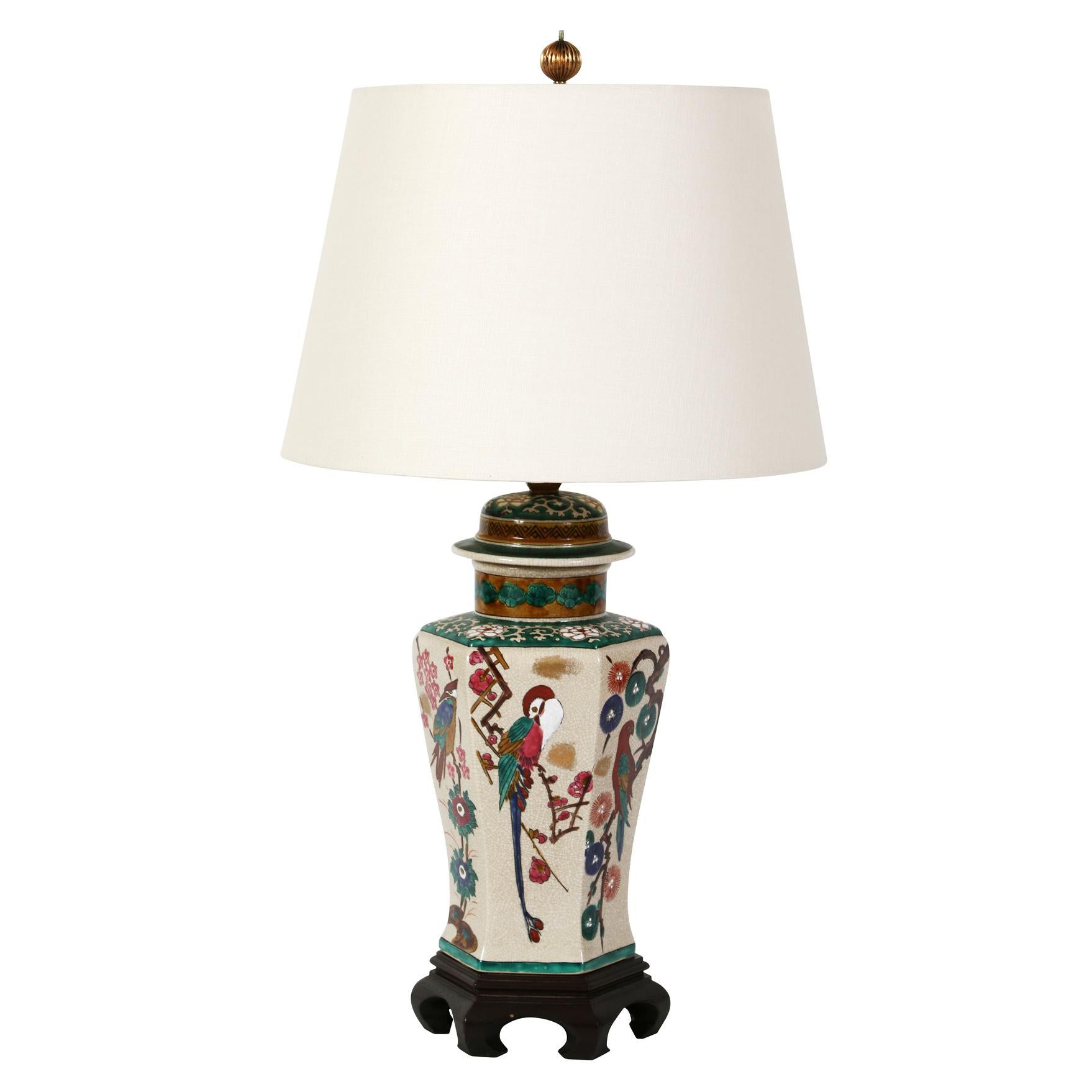 A pair of decorative Chinese export lamps decorated with flowers, branches and birds in shades of green, blue and red.
