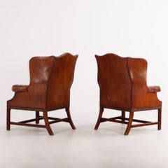 A pair of Chippendale style leather wing chairs C 1910.