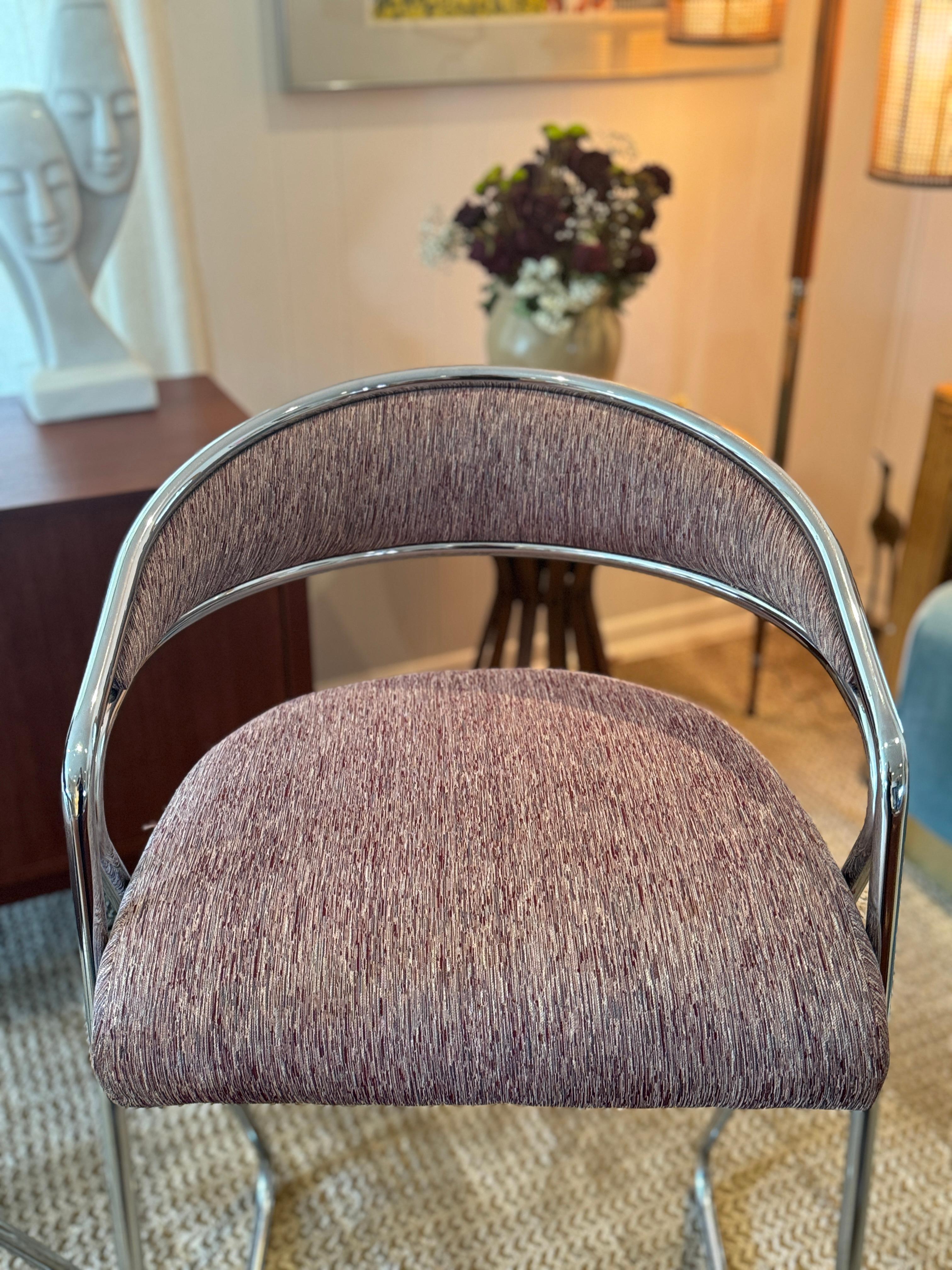 A pair of chrome bar stools attributed to Milo Baughman, circa 1970s. Their sculptural chrome frames create a floating effect, give them a timeless appeal that still feels relevant today. The original fabric—an elegant blend of purples, pinks, and