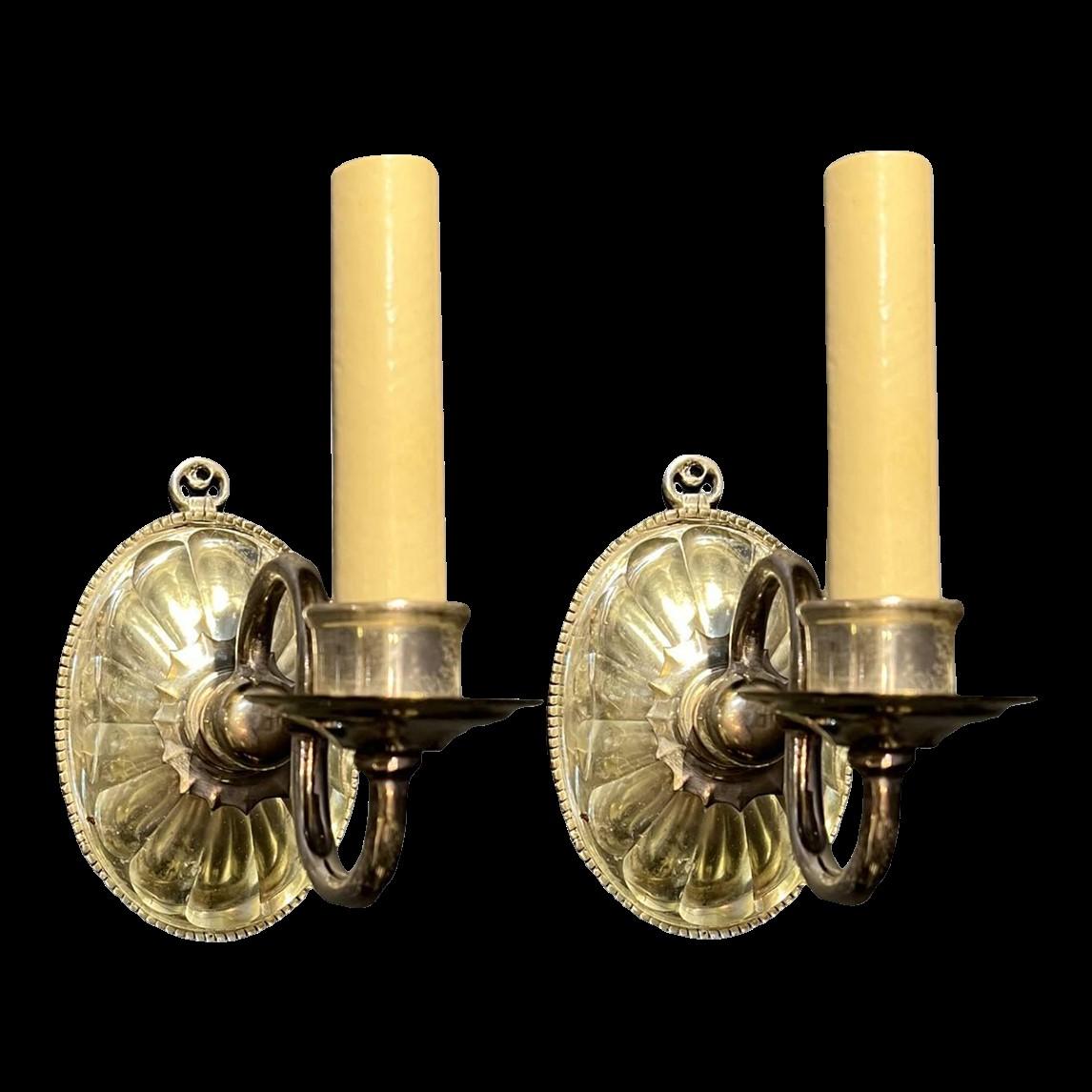 A pair of circa 1920's Caldwell silver plated one light sconces with molded glass backplate